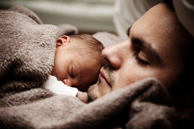 Ein Baby schläft auf der Brust seines Vaters. | Quelle: Shutterstock