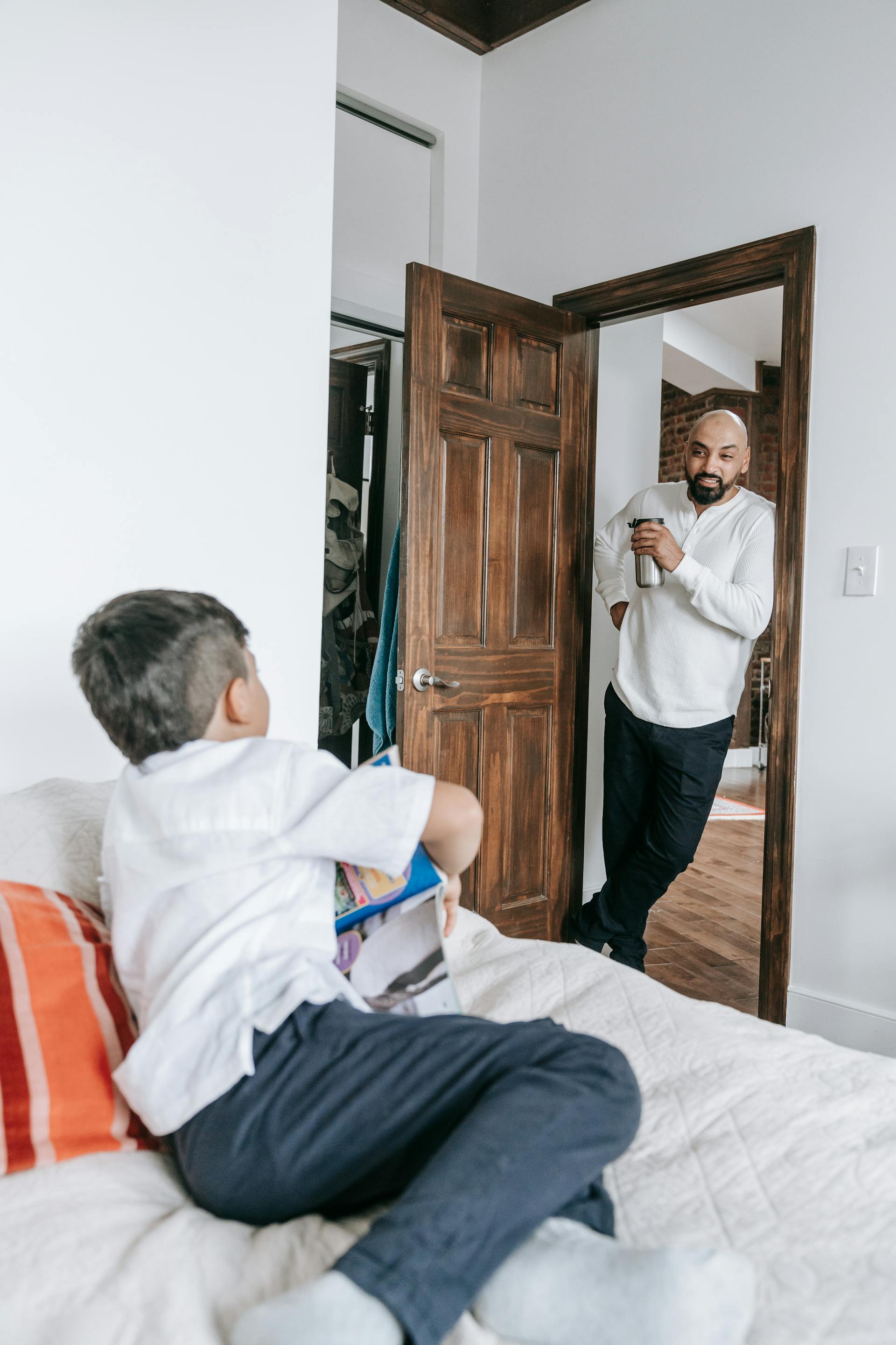 Ein Vater im Gespräch mit seinem kleinen Sohn zu Hause | Quelle: Pexels