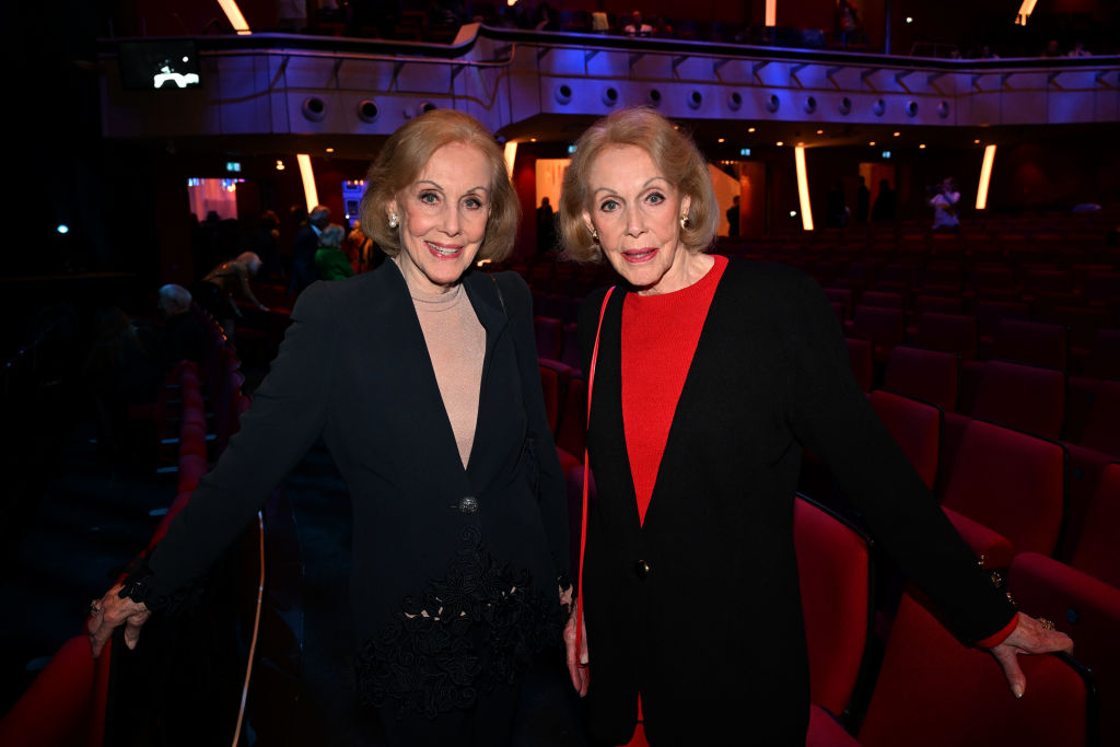 09. Mai 2024, Bayern, München: Die Kessler-Zwillinge Alice und Ellen Kessler stehen in der Pause der Münchner Premiere des Ralph-Siegel-Musicals „Ein bisschen Frieden“ im Deutschen Theater zwischen den Stuhlreihen. | Quelle: Getty Images