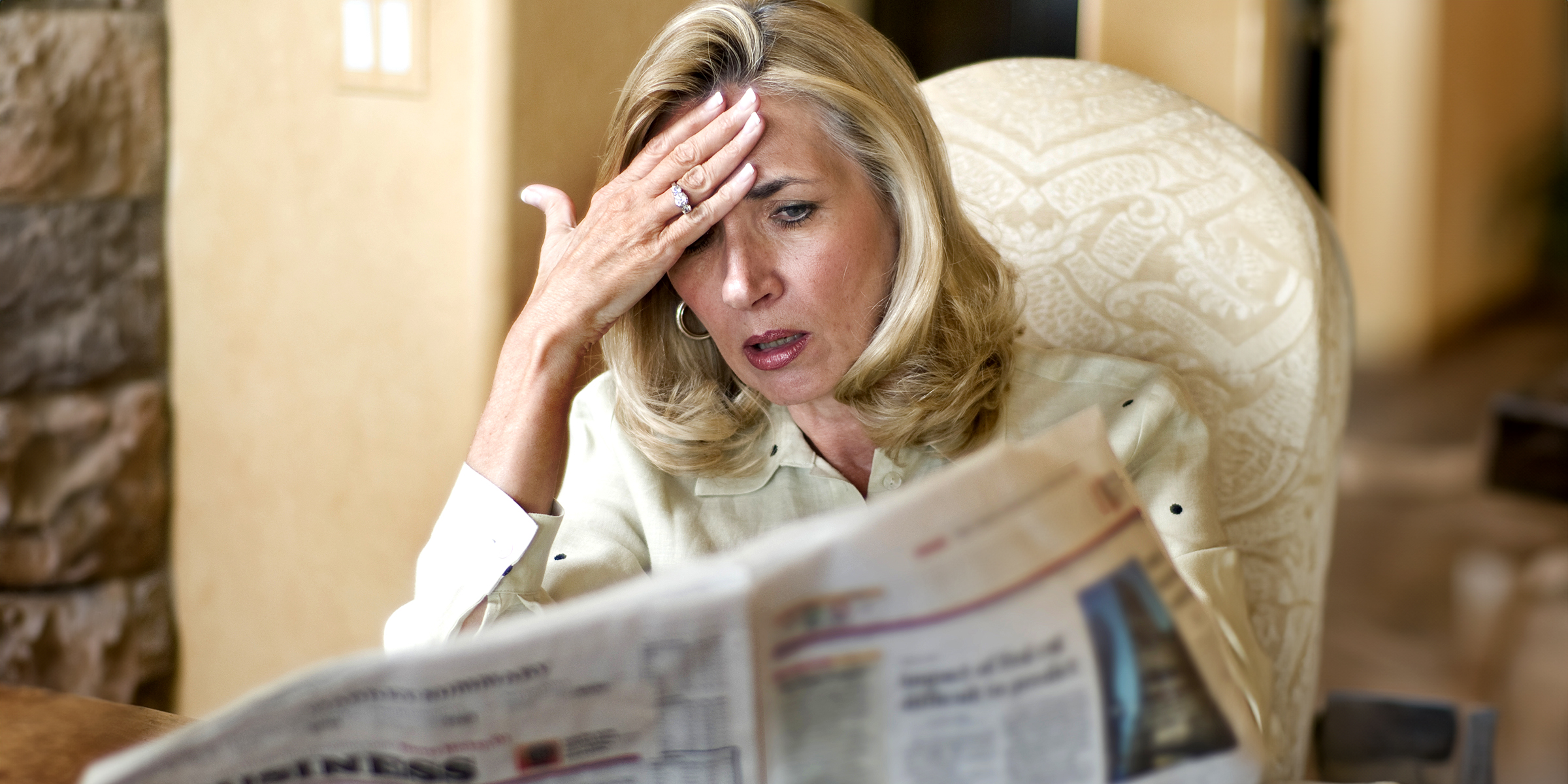 Eine geschockte Frau, die eine Zeitung liest | Quelle: Shutterstock