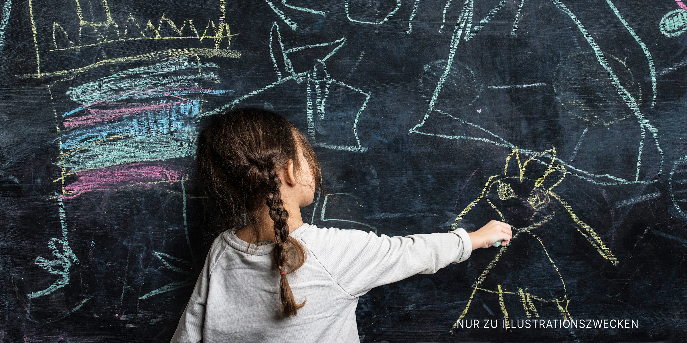 Kleines Mädchen schreibt auf eine Kreidetafel | Quelle: Getty Images