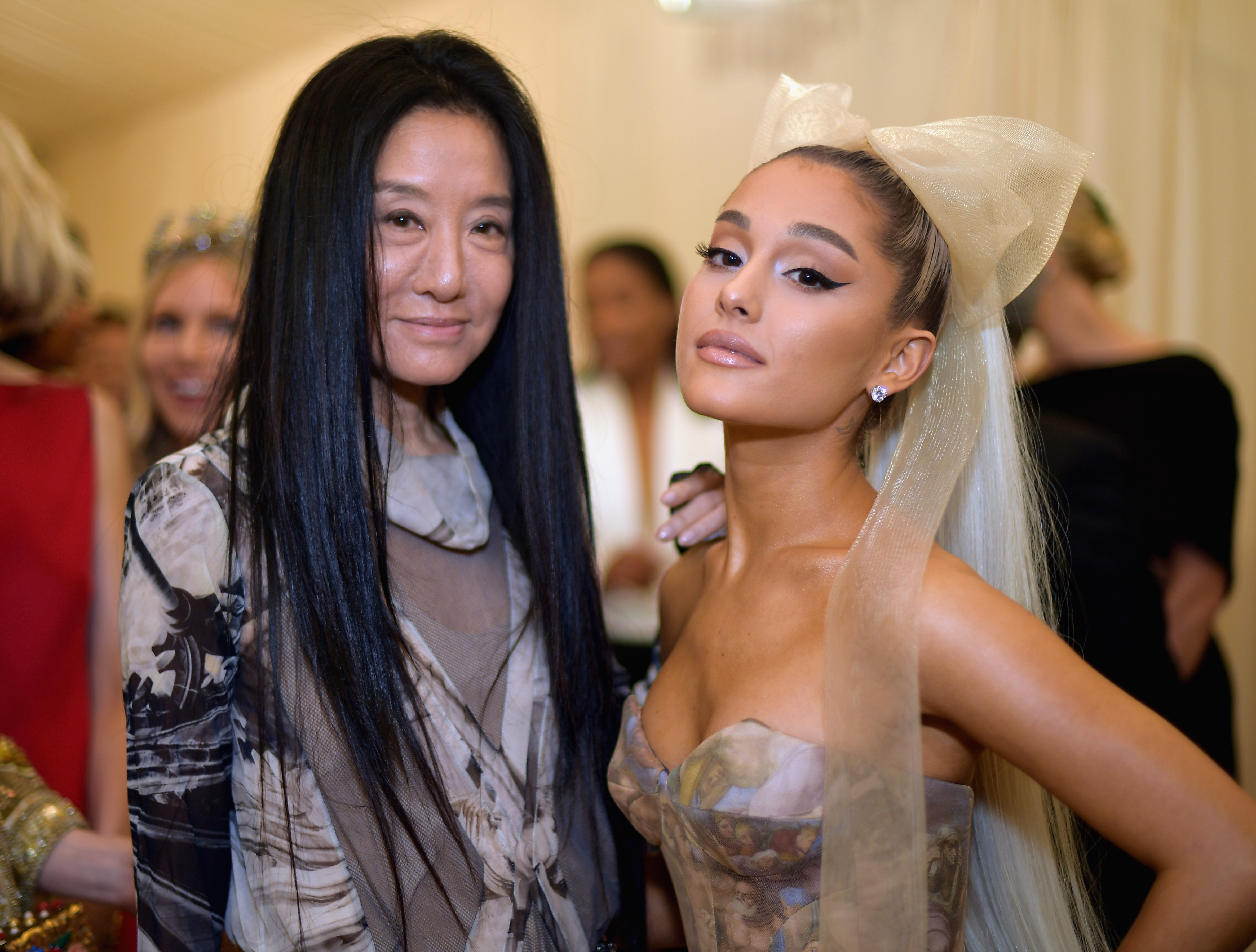 Vera Wang und Ariana Grande posierten gemeinsam im Metropolitan Museum of Art während der „Heavenly Bodies: Fashion & The Catholic Imagination“-Gala des Costume Institute am 7. Mai 2018 in New York City. Wang, die das von der Sixtinischen Kapelle inspirierte Ballkleid der Sängerin maßgeschneidert hatte, stand neben Grande und trug ein luftiges, bedrucktes, transparentes Langarm-Oberteil über neutralen Schichten, während der Popstar mit einem dramatischen Flügel-Eyeliner, einem platinblonden Pferdeschwanz und einer übergroßen champagnerfarbenen Tüllschleife am Kopf glänzte. | Quelle: Getty Images
