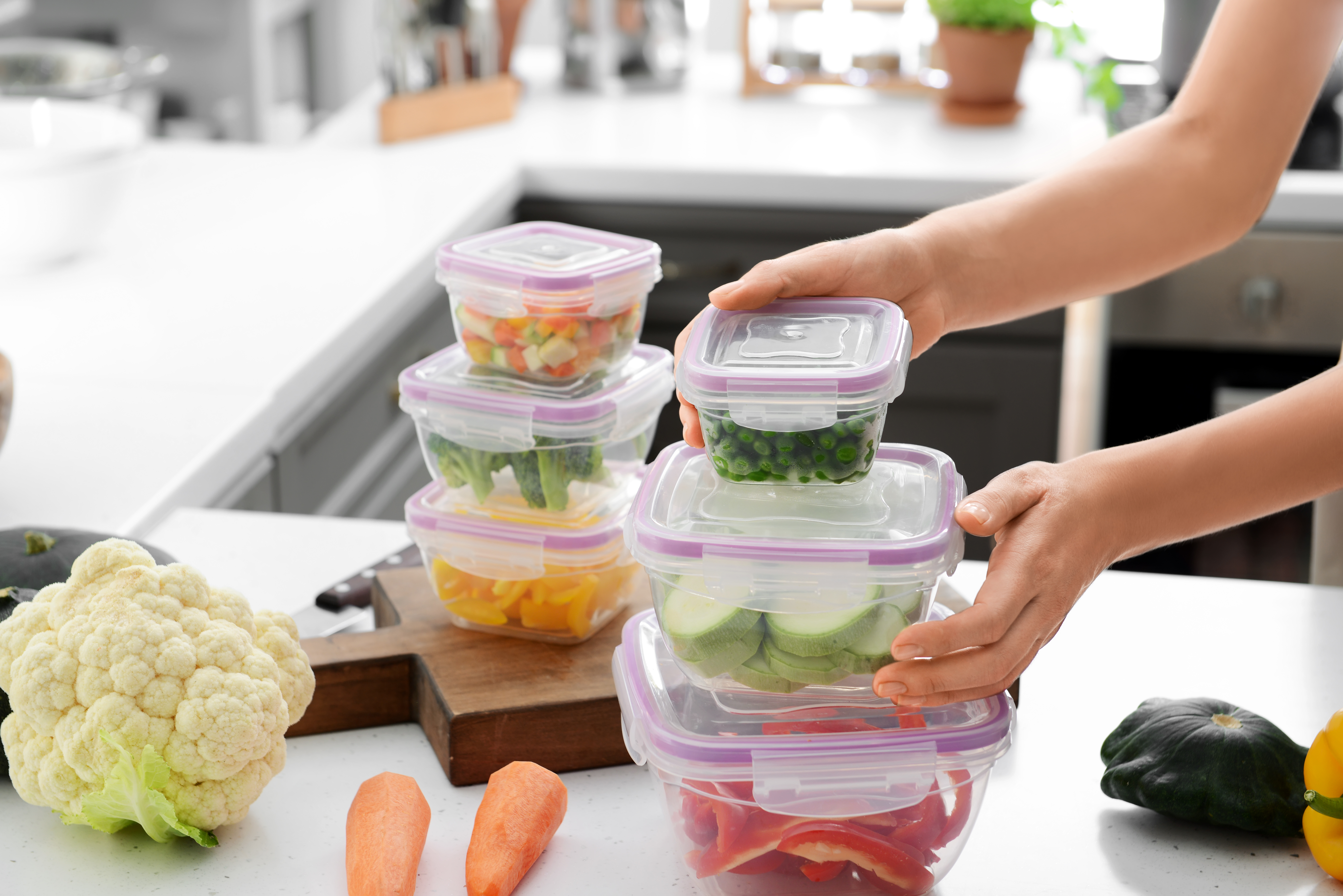 Frau hält einen Stapel Plastikbehälter mit frischem Gemüse zum Einfrieren | Quelle: Shutterstock