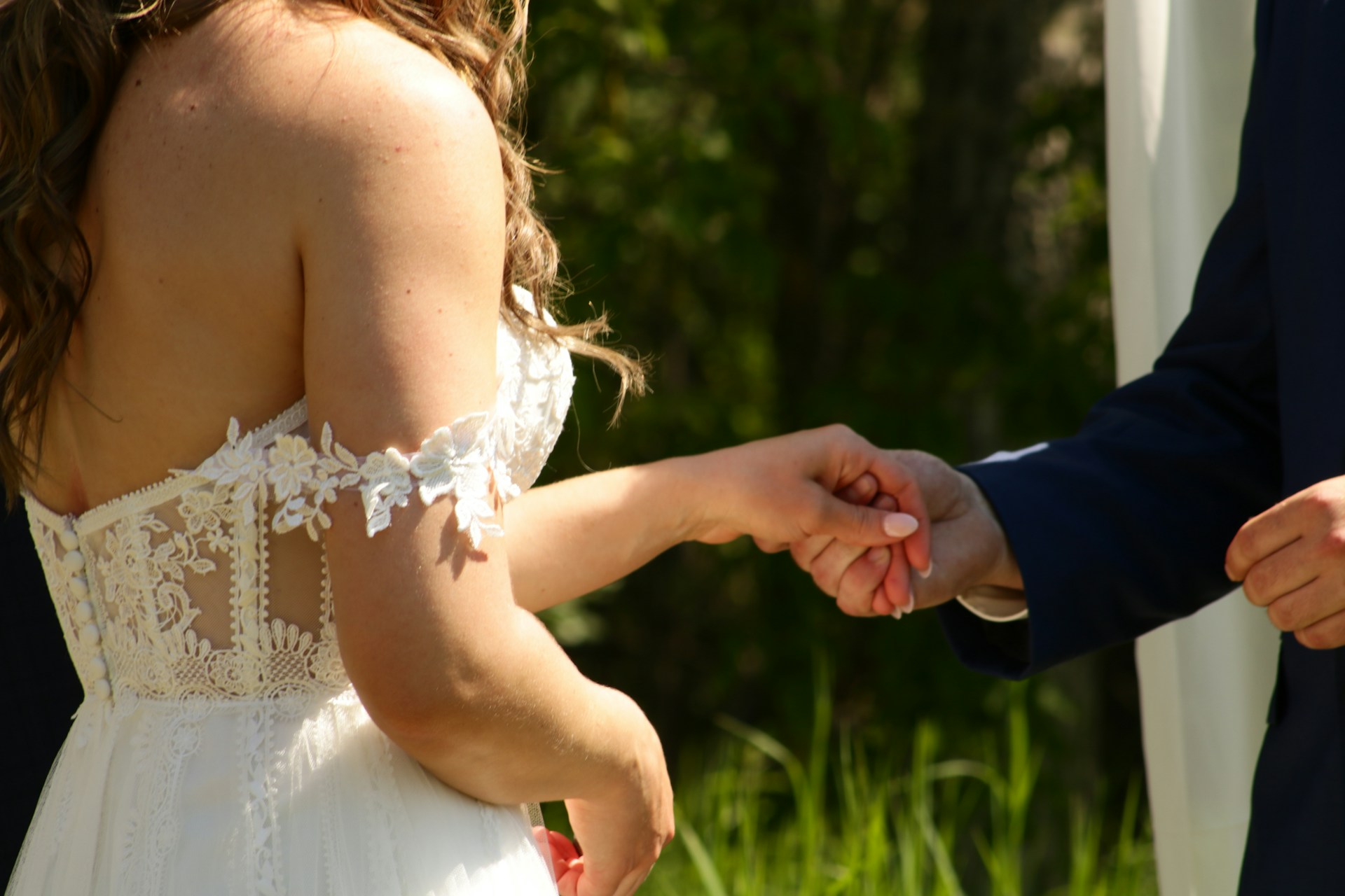 Ausgeschnittene Aufnahme eines Bräutigams, der die Hand der Braut hält | Quelle: Unsplash