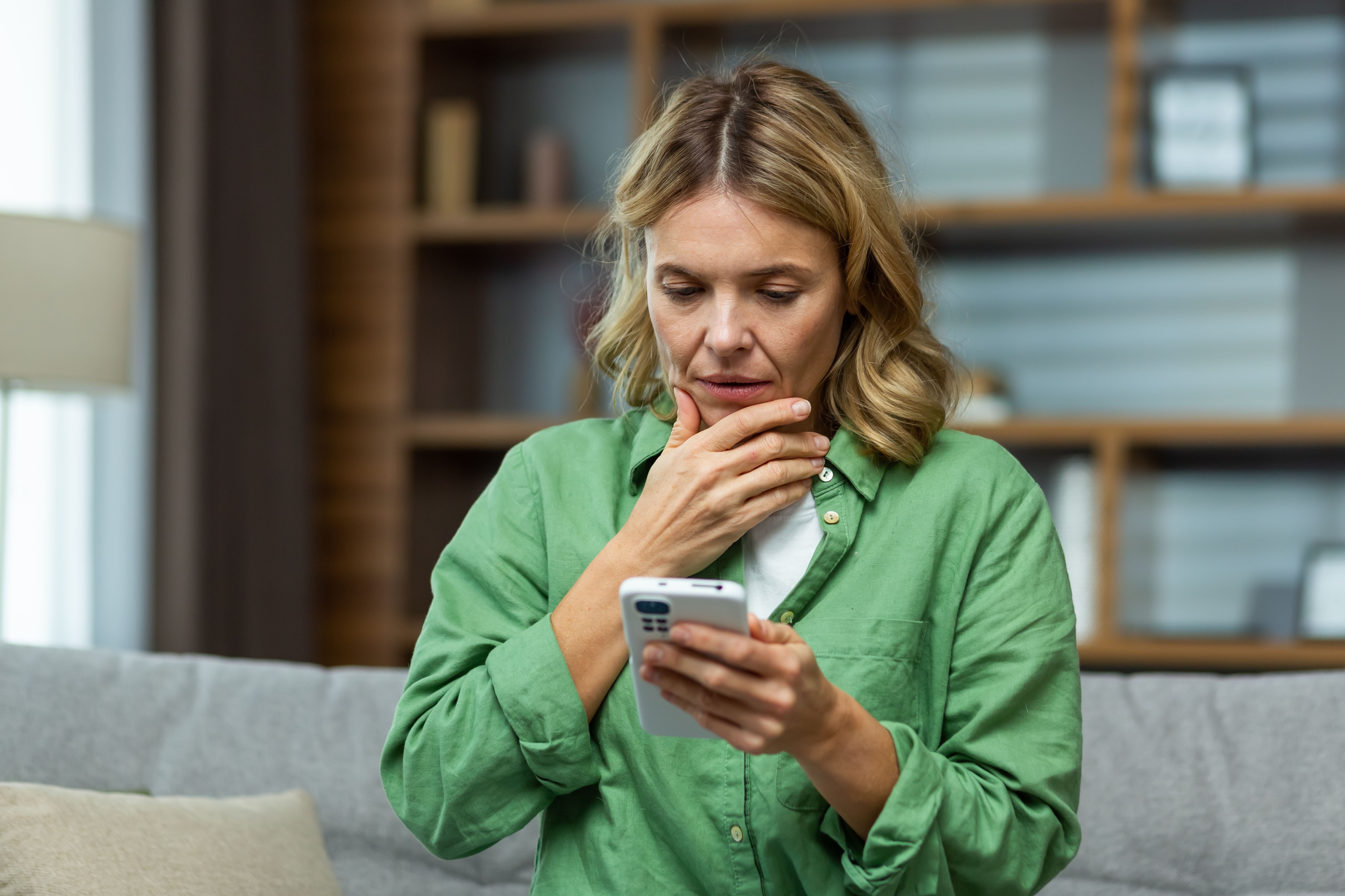 Eine Frau mittleren Alters schaut besorgt, während sie ihr Telefon hält | Quelle: Shutterstock