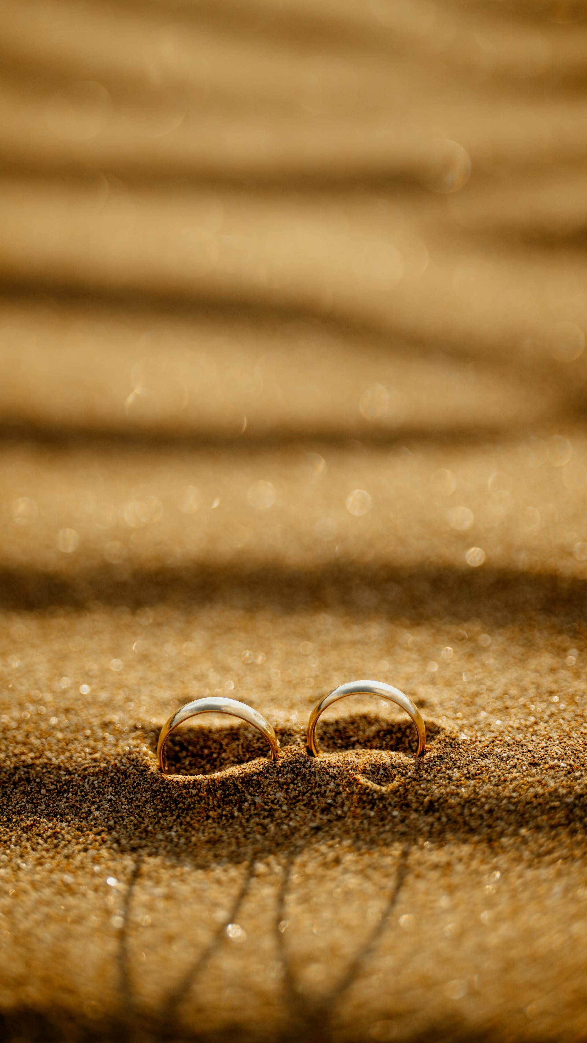 Eheringe an einem Sandstrand bei Sonnenuntergang | Quelle: Pexels