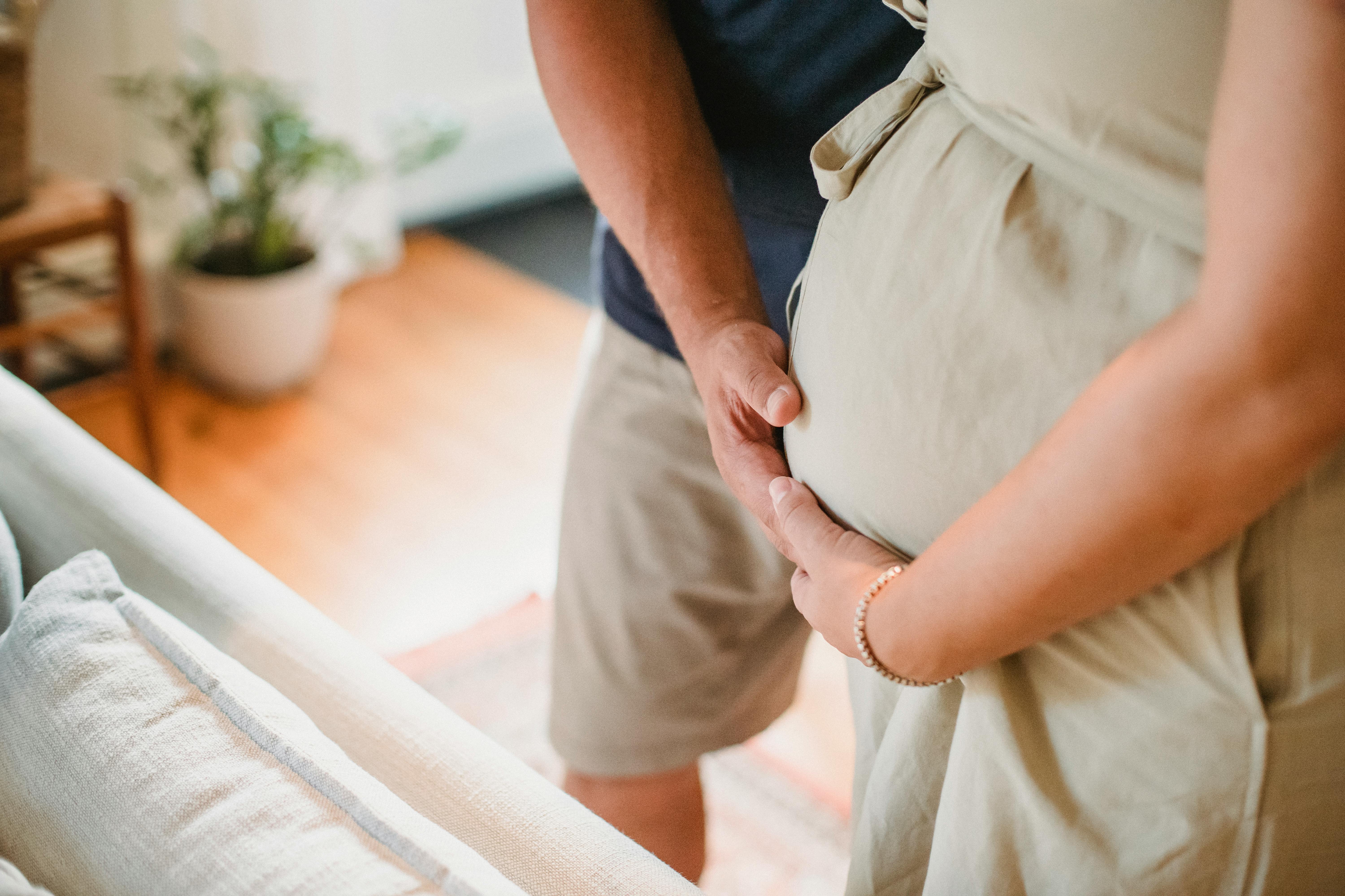 Ein Mann und eine Frau streicheln einen schwangeren Bauch | Quelle: Pexels