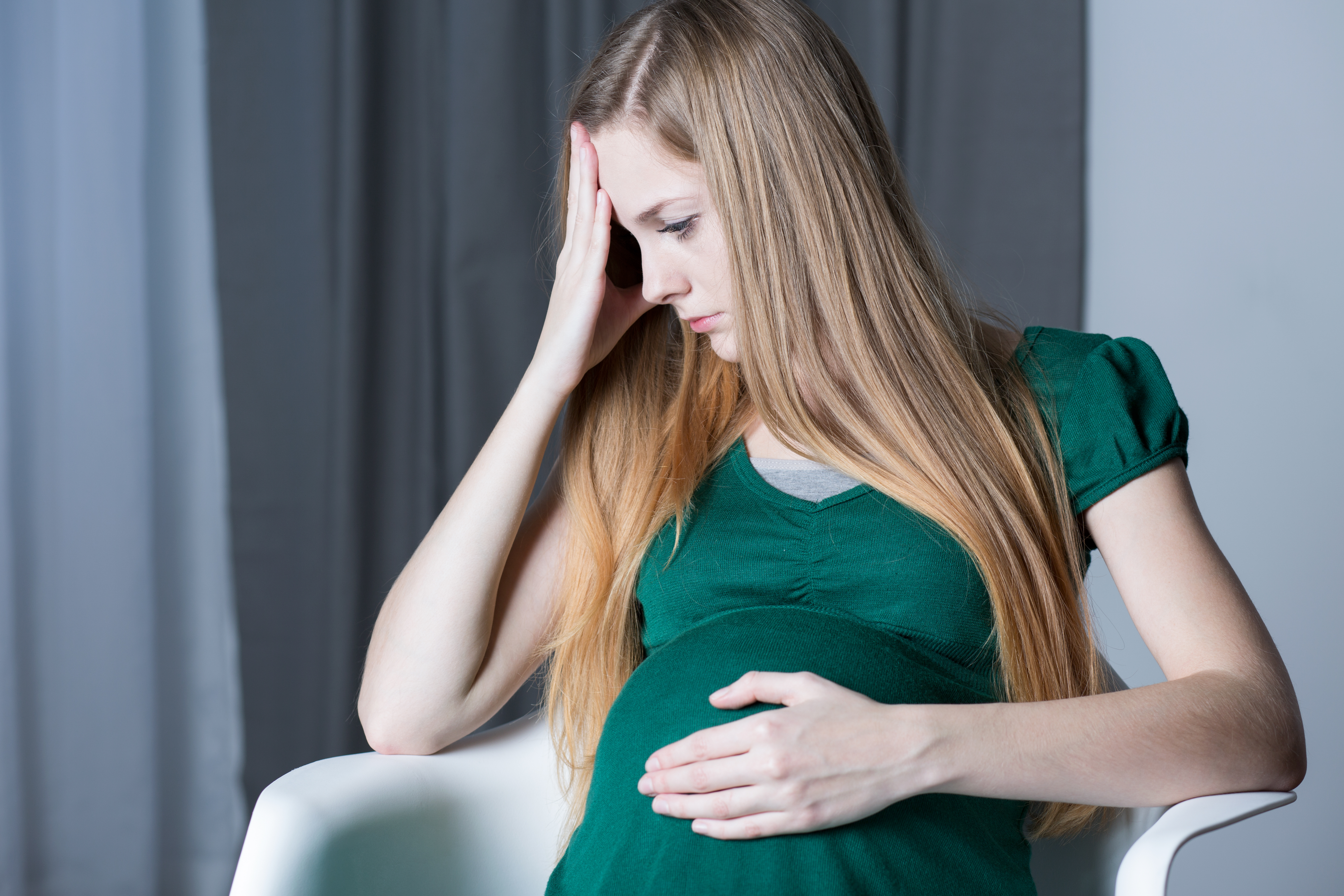Eine aufgeregte schwangere Frau, die sich den Kopf und den Bauch hält | Quelle: Shutterstock