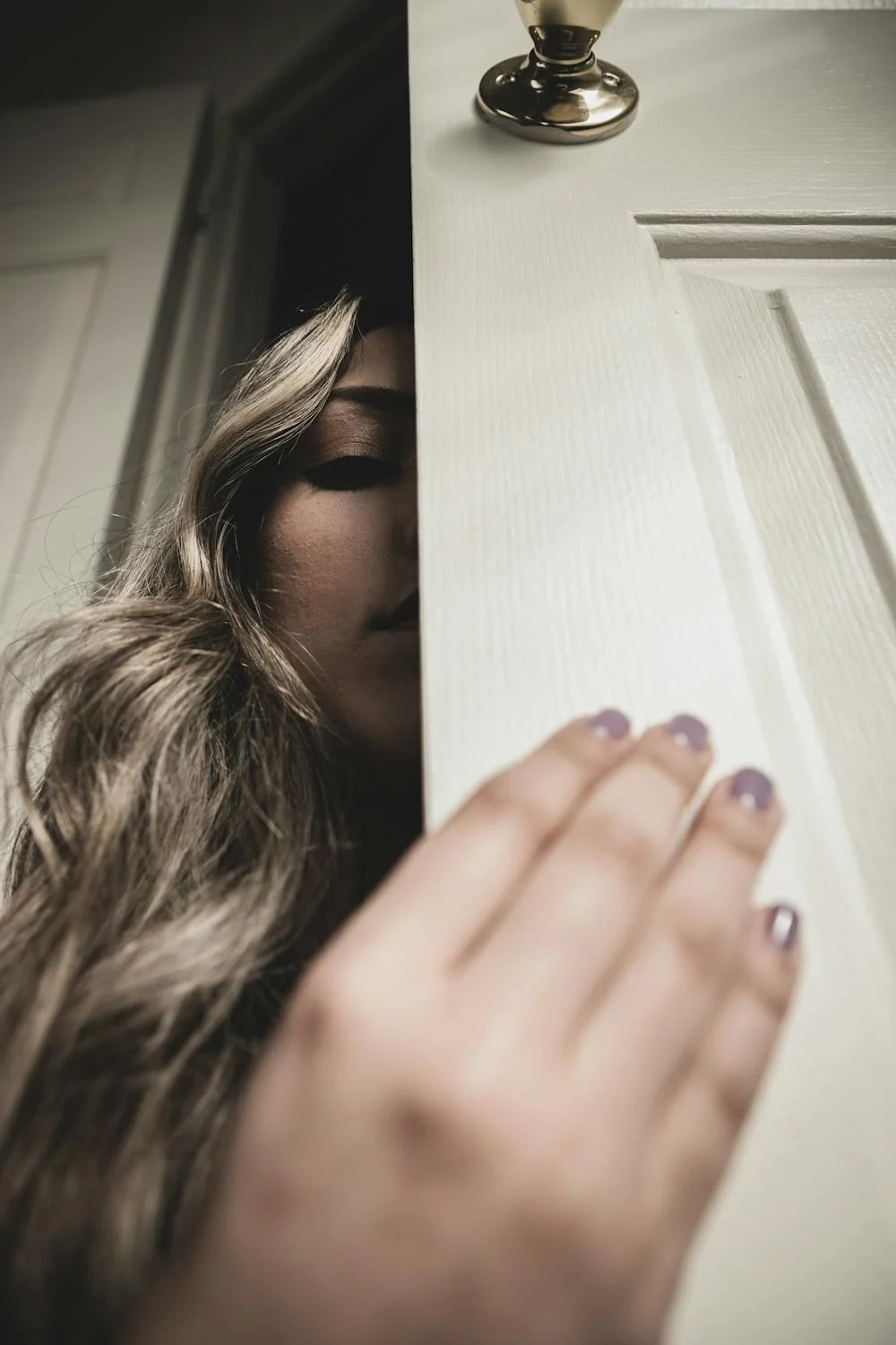 Eine Frau späht hinter einer Tür | Quelle: Pexels
