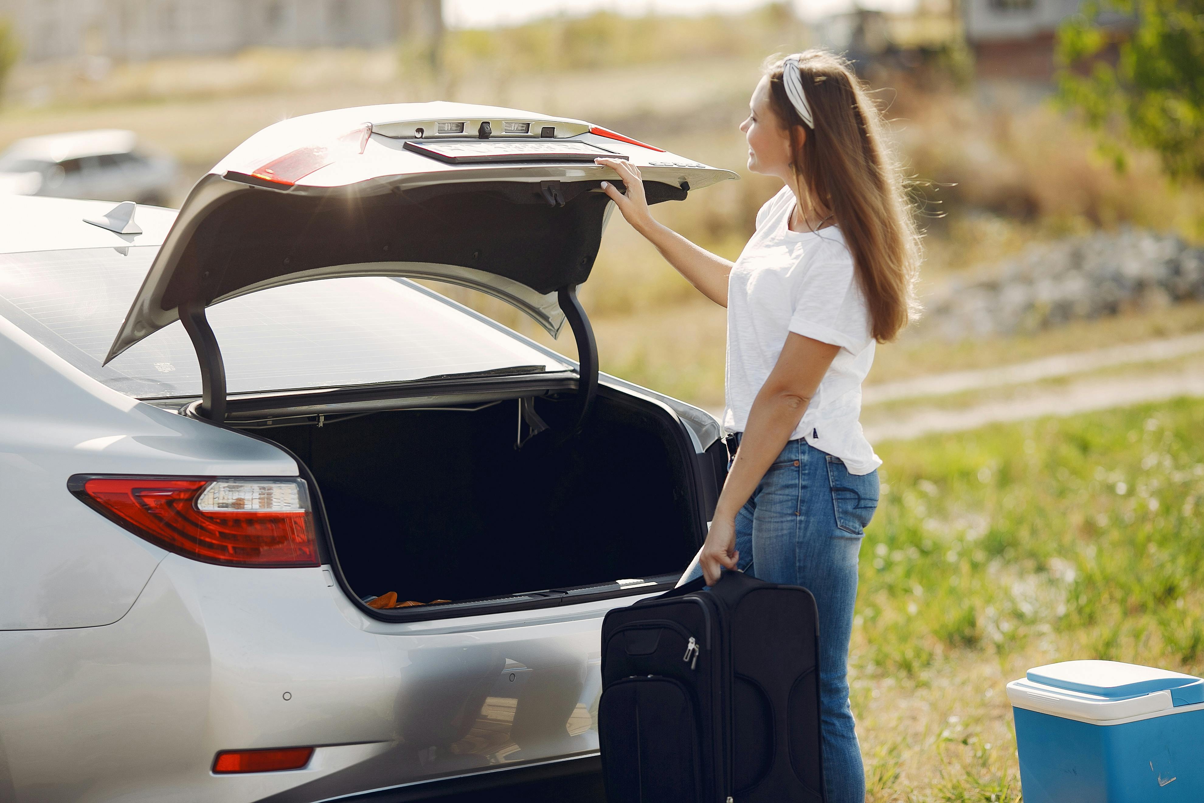 Eine Frau steht mit ihrem Gepäck neben einem Auto | Quelle: Pexels