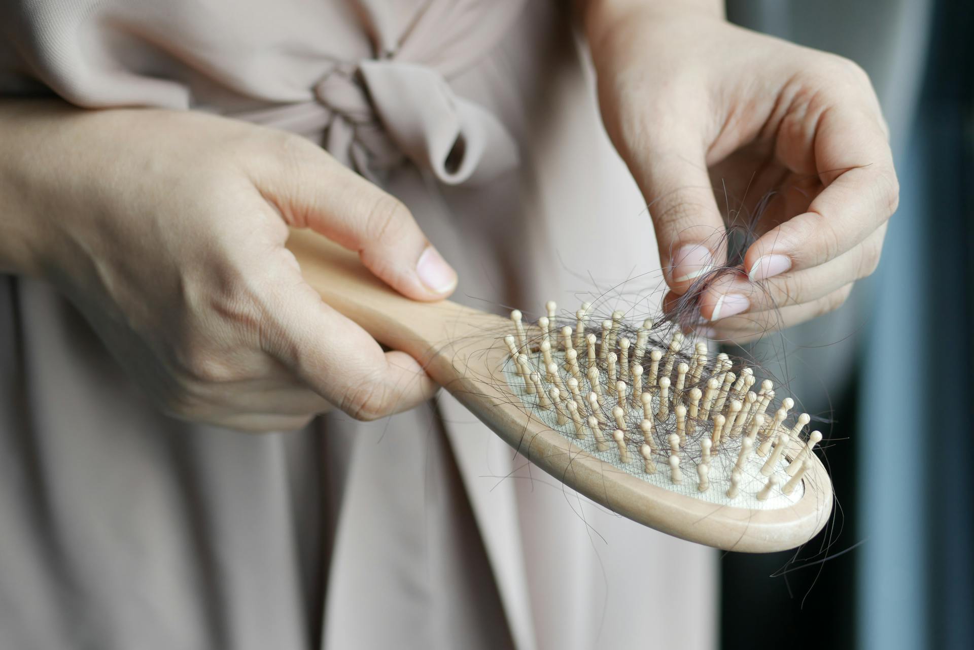 Abgeschnittene Aufnahme einer Frau, die Haare aus einer Bürste entfernt | Quelle: Pexels