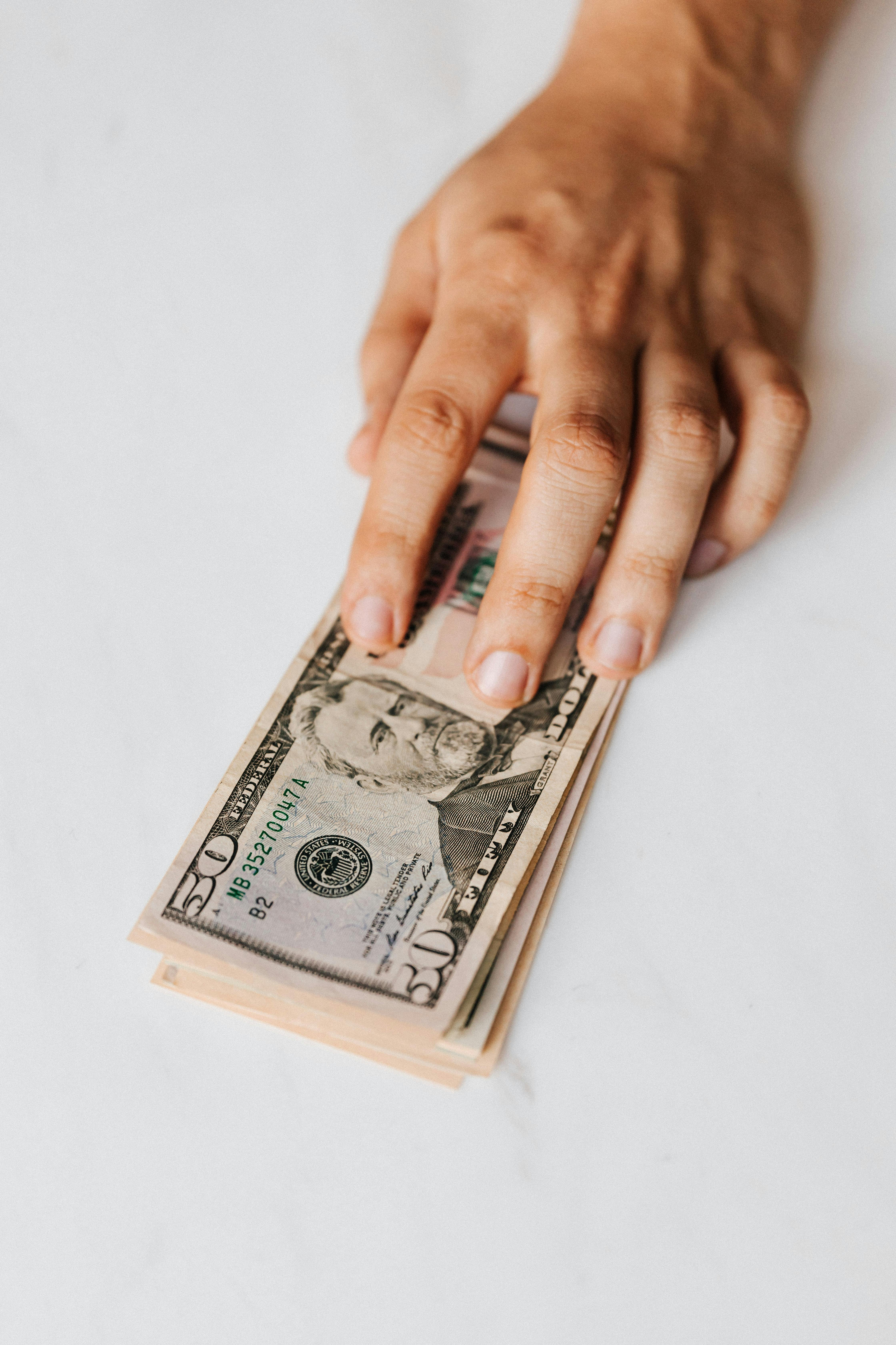 Eine Person legt einen Stapel Papiergeld auf den Tisch | Quelle: Pexels