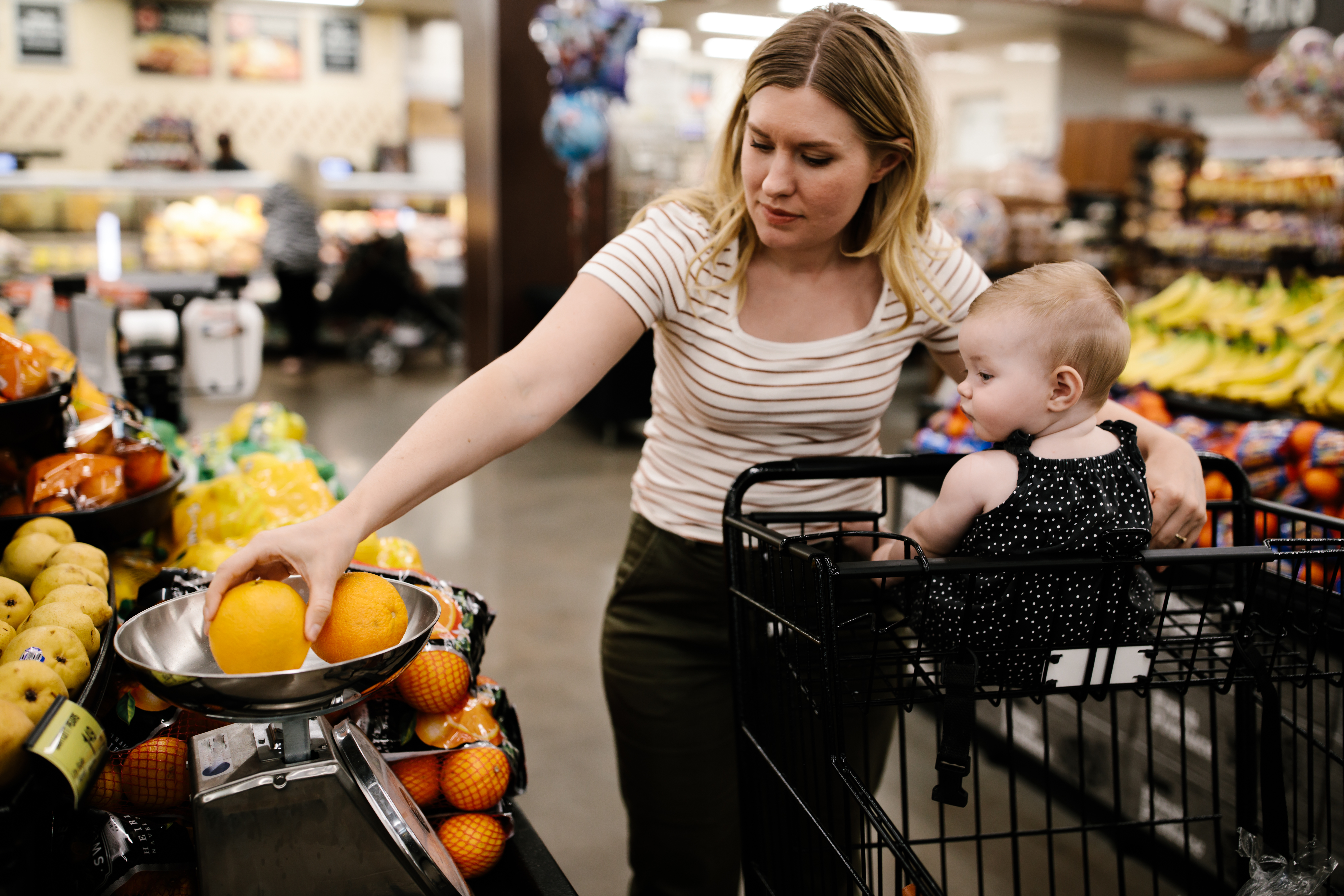 Mutter mit ihrer kleinen Tochter beim Einkaufen von frischem Obst im Supermarkt | Quelle: Getty Images