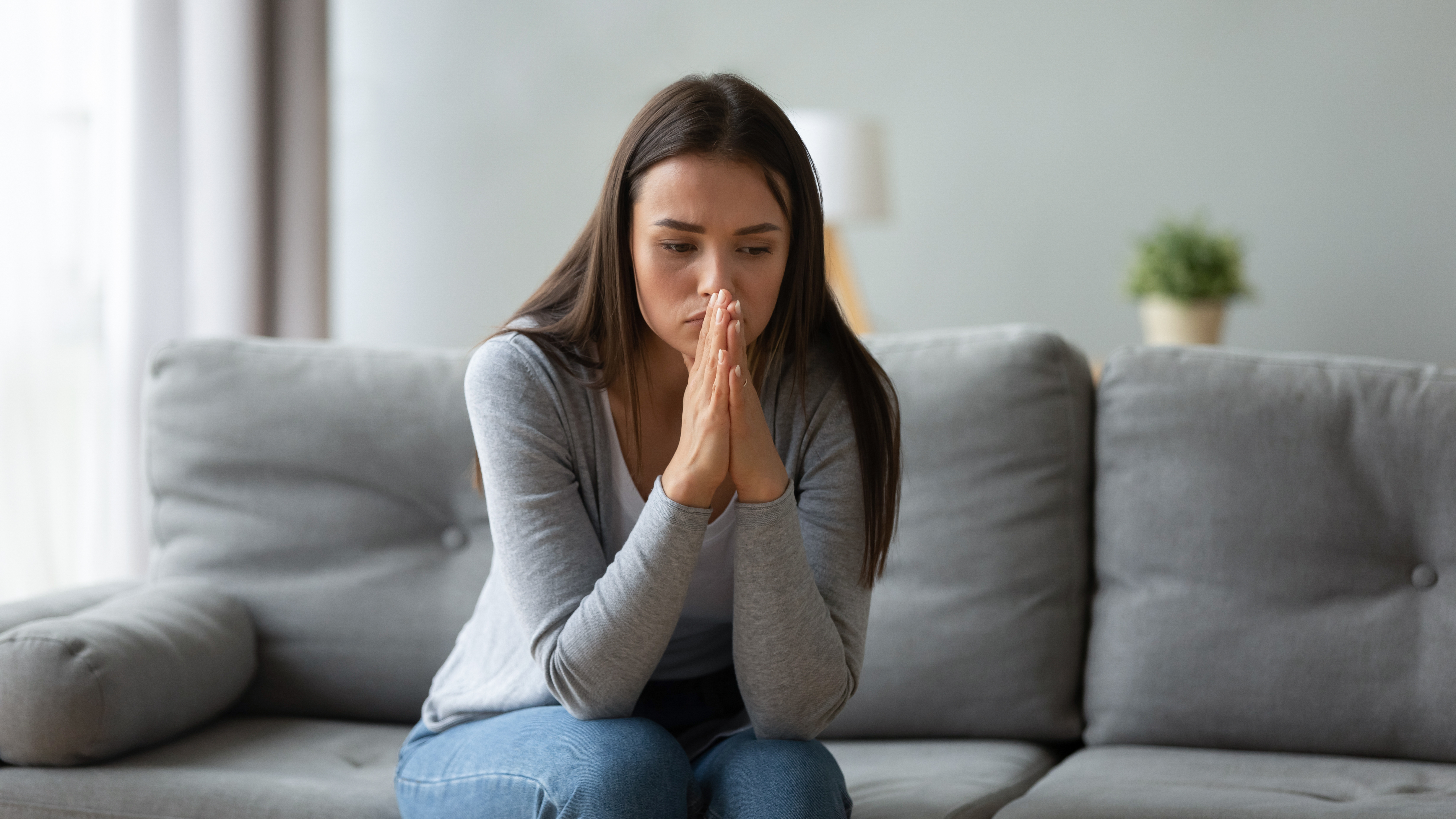 Eine verzweifelte Frau sitzt auf dem Sofa | Quelle: Shutterstock
