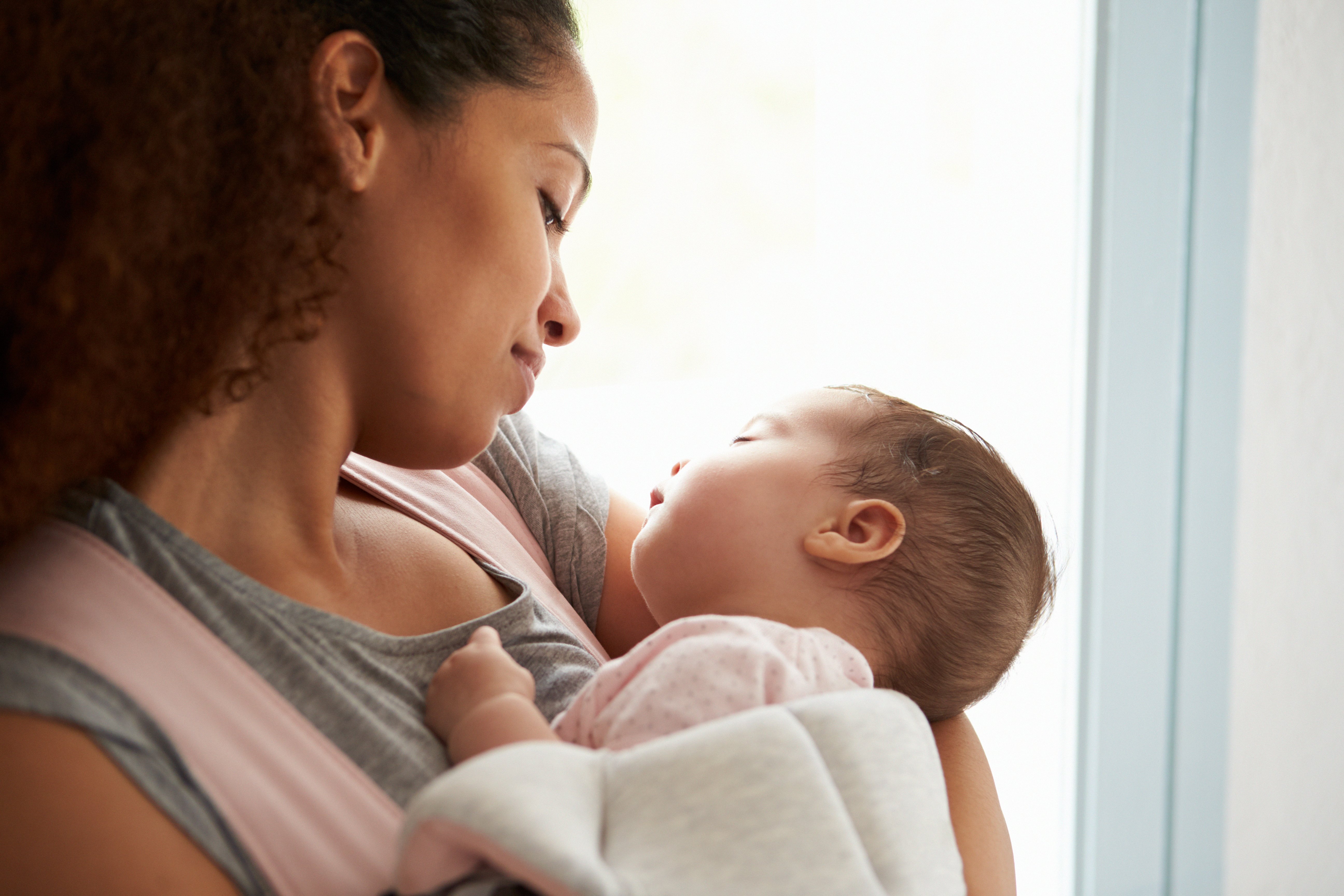 Nahaufnahme der Mutter, die Baby-Tochter zu Hause kuschelt | Quelle: Shutterstock
