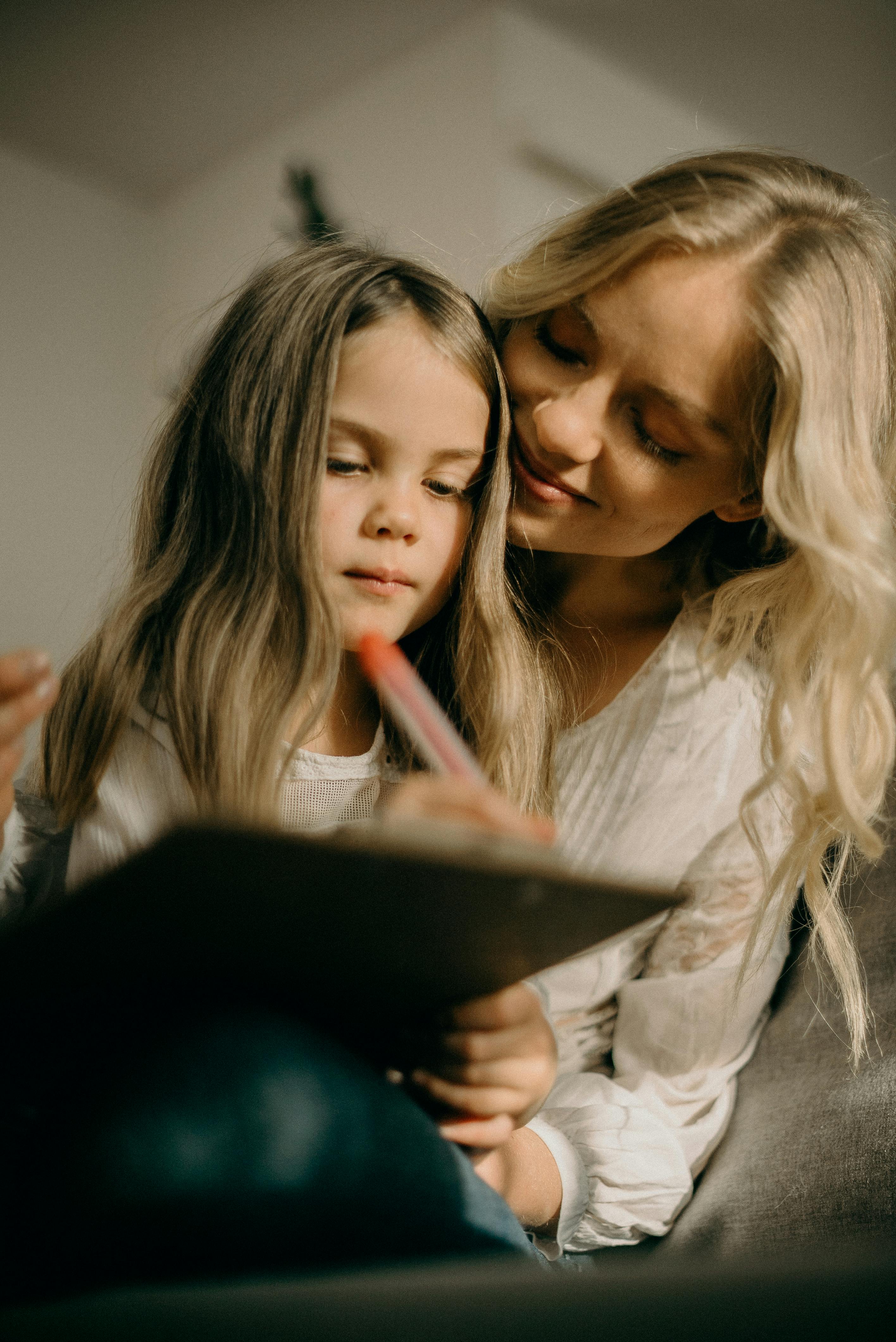 Ein kleines Mädchen, das etwas schreibt, während seine Mutter es beobachtet | Quelle: Pexels