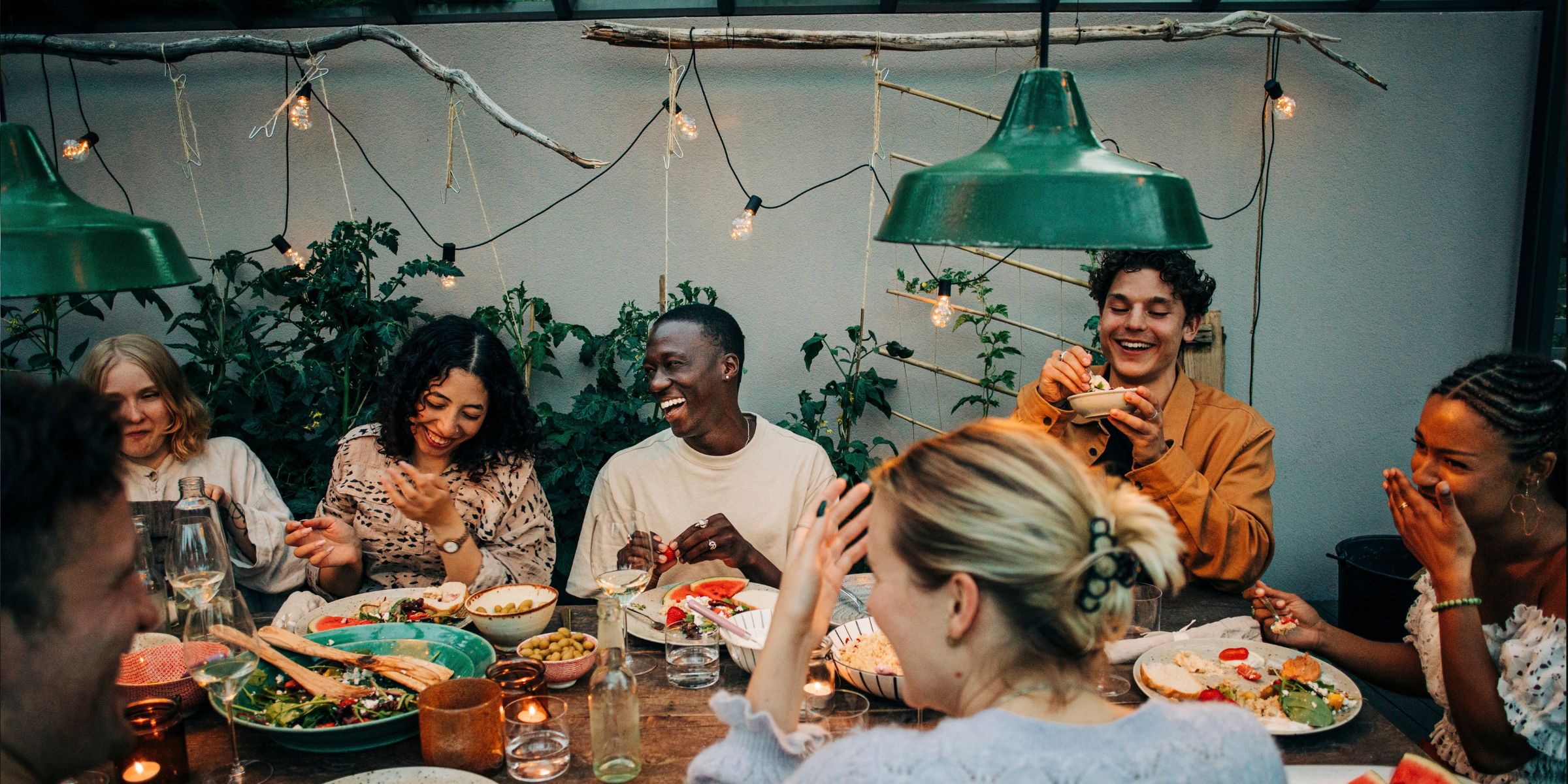 Fröhliche Arbeitskollegen beim gemeinsamen Abendessen im Garten | Quelle: Getty Images