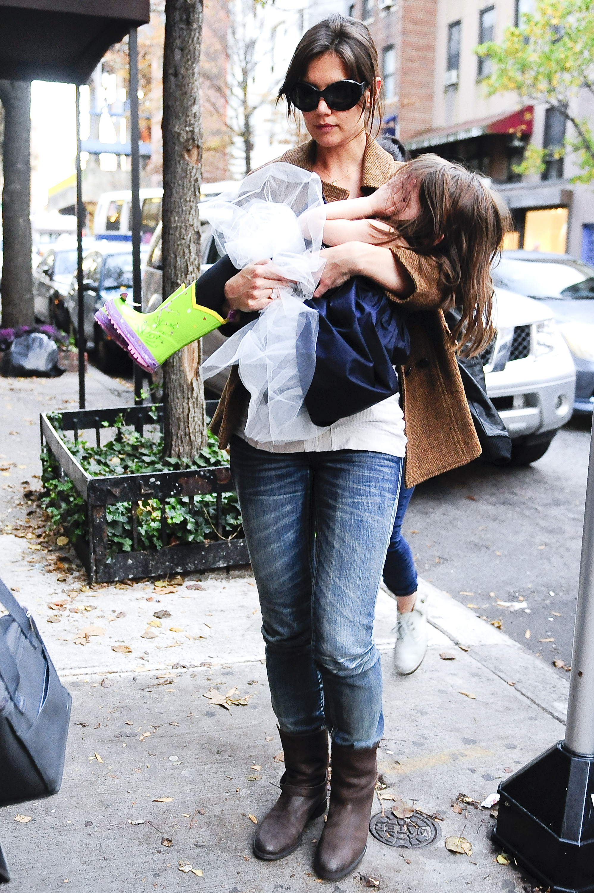 Katie Holmes trägt Suri Cruise, die ihr Gesicht bedeckt, während sie am 22. November 2009 durch Greenwich Village spazieren | Quelle: Getty Images