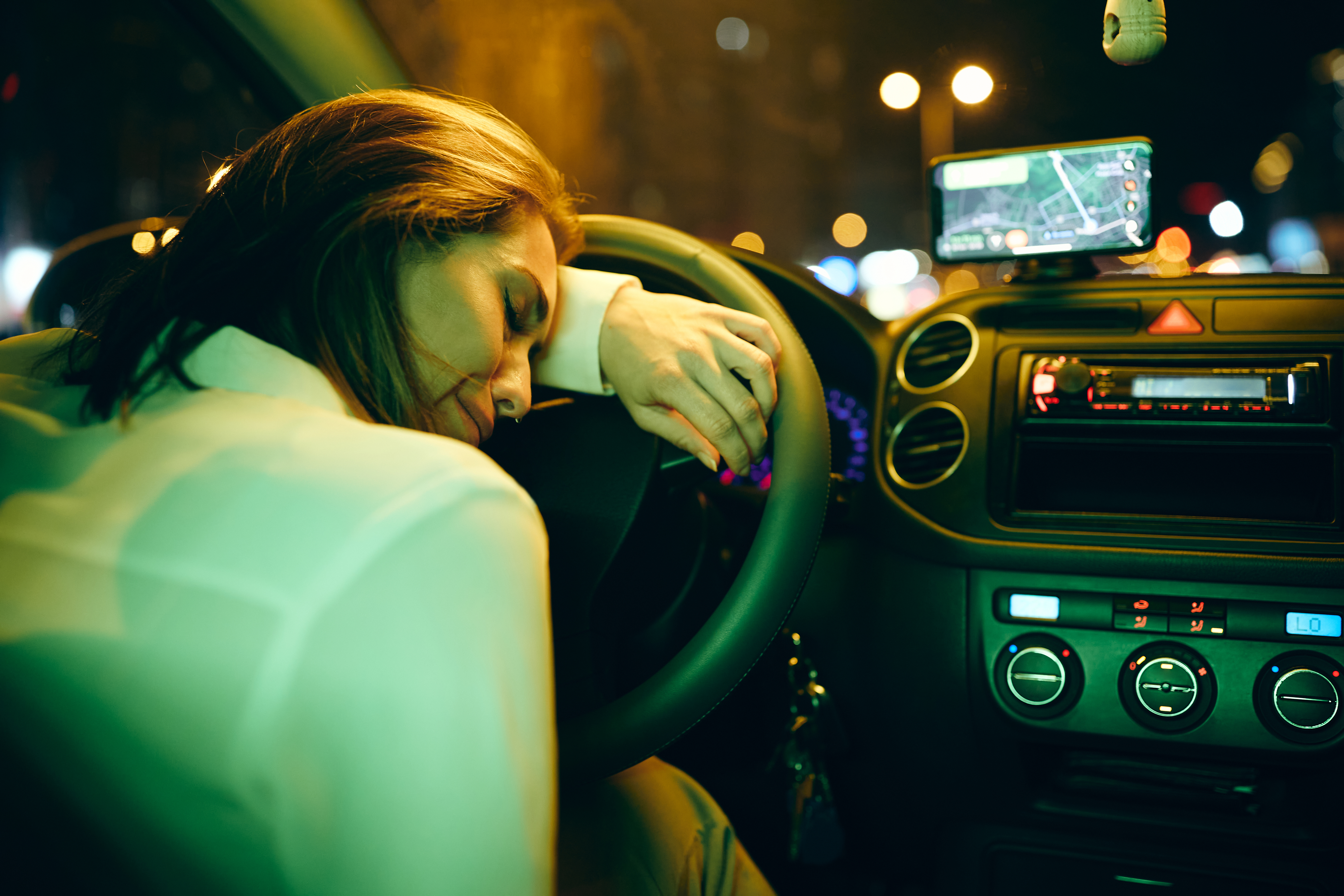 Depressive junge Frau lehnt am Lenkrad eines Autos und weint | Quelle: Shutterstock