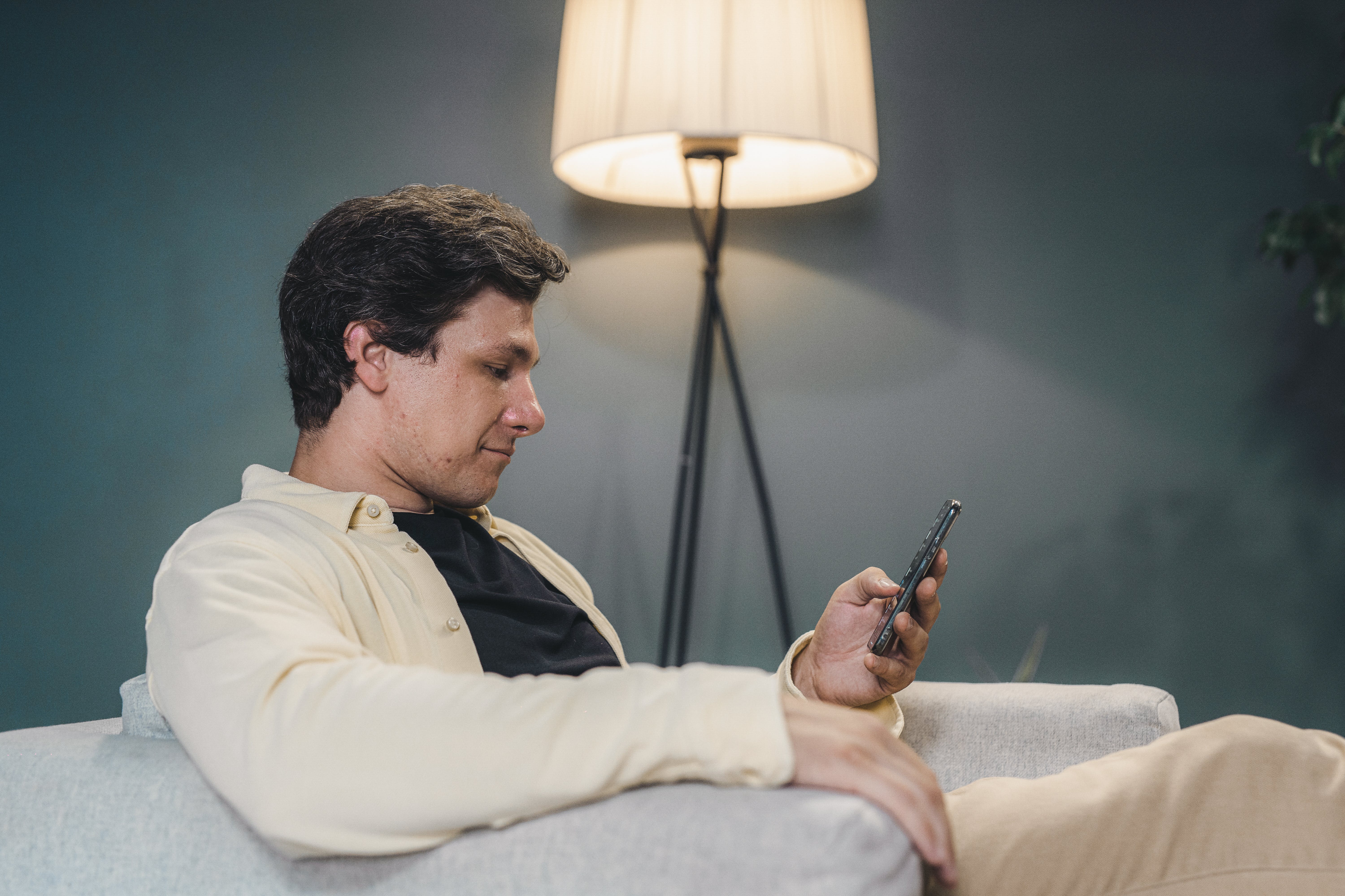 Ein Mann sitzt auf einem Sofa und benutzt ein Smartphone | Quelle: Pexels