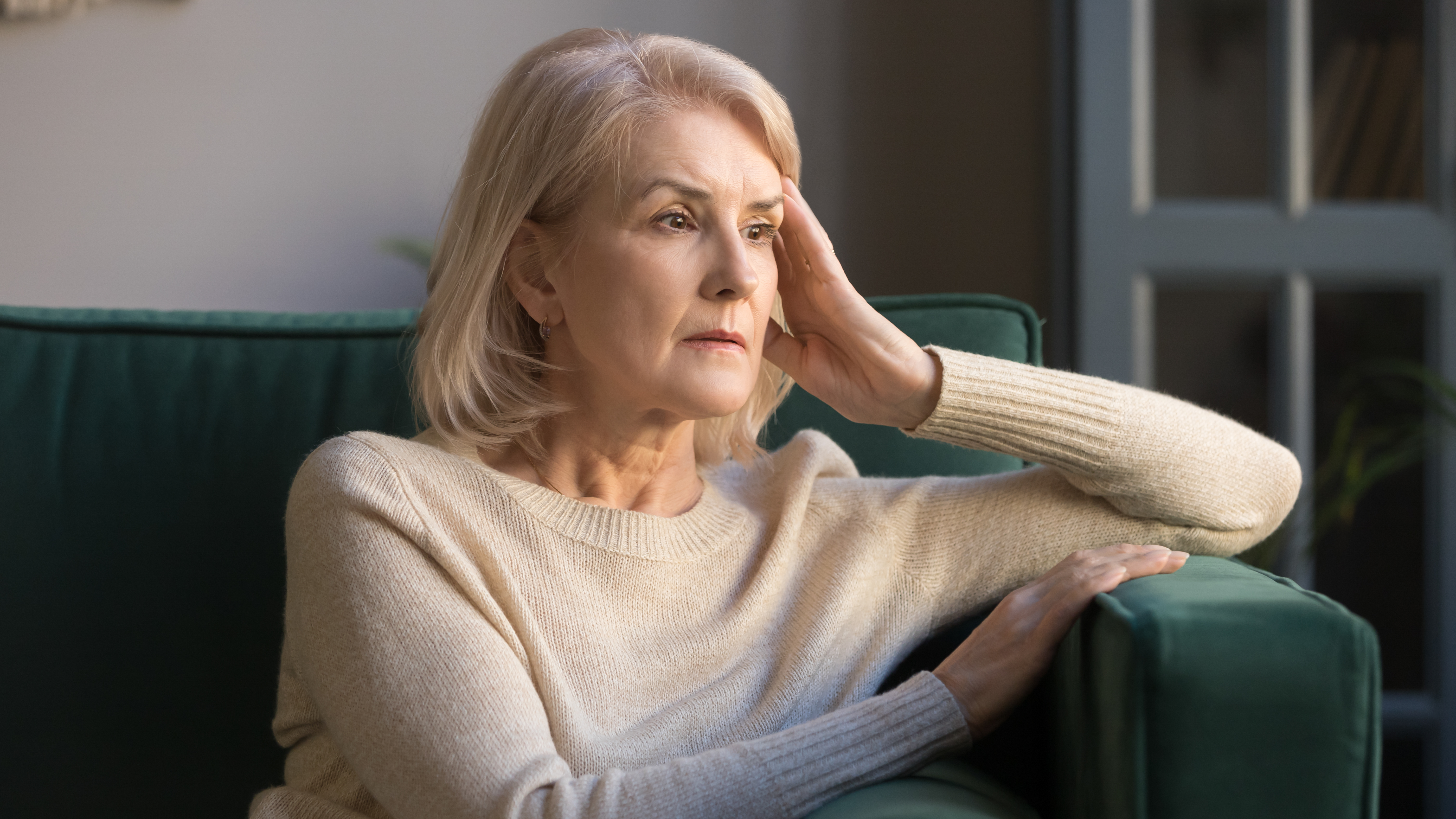 Eine depressive ältere Frau, die auf einem Sofa sitzt | Quelle: Shutterstock