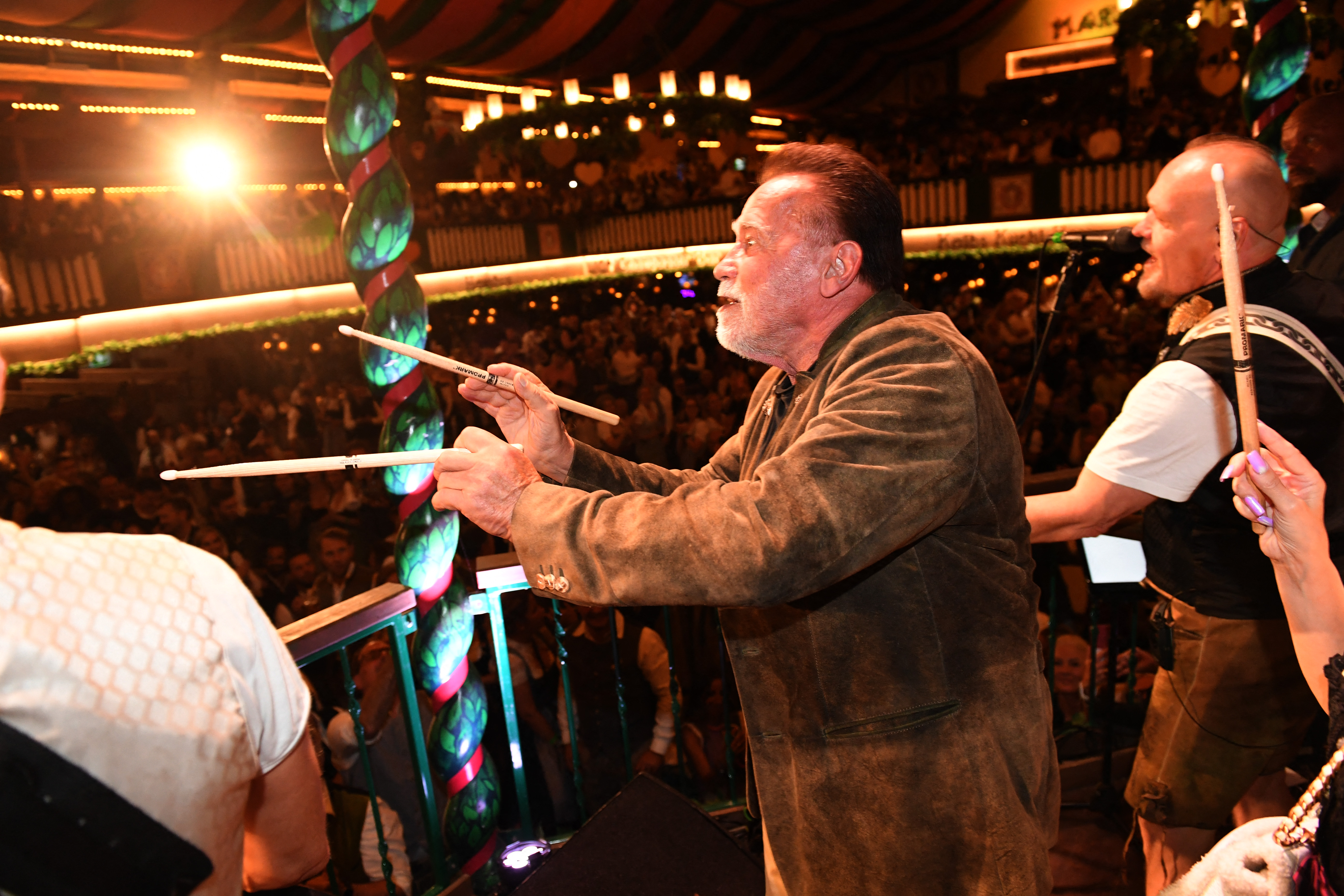 Arnold Schwarzenegger steht am 22. September 2026 beim Oktoberfest im Festzelt auf der Bühne und dirigiert die Band | Quelle: Getty Images