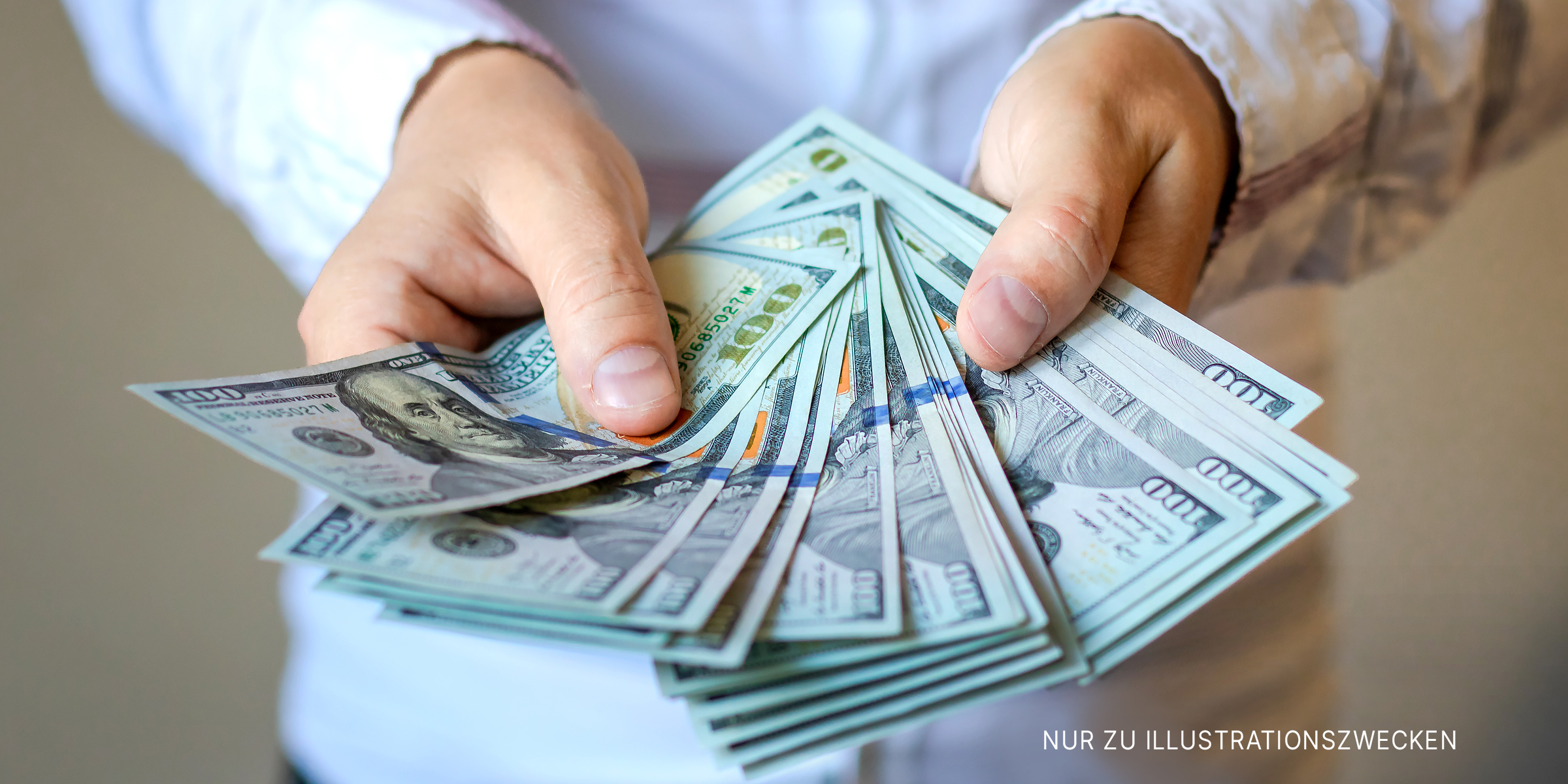 Eine Person mit Dollarscheinen in der Hand | Quelle: Shutterstock