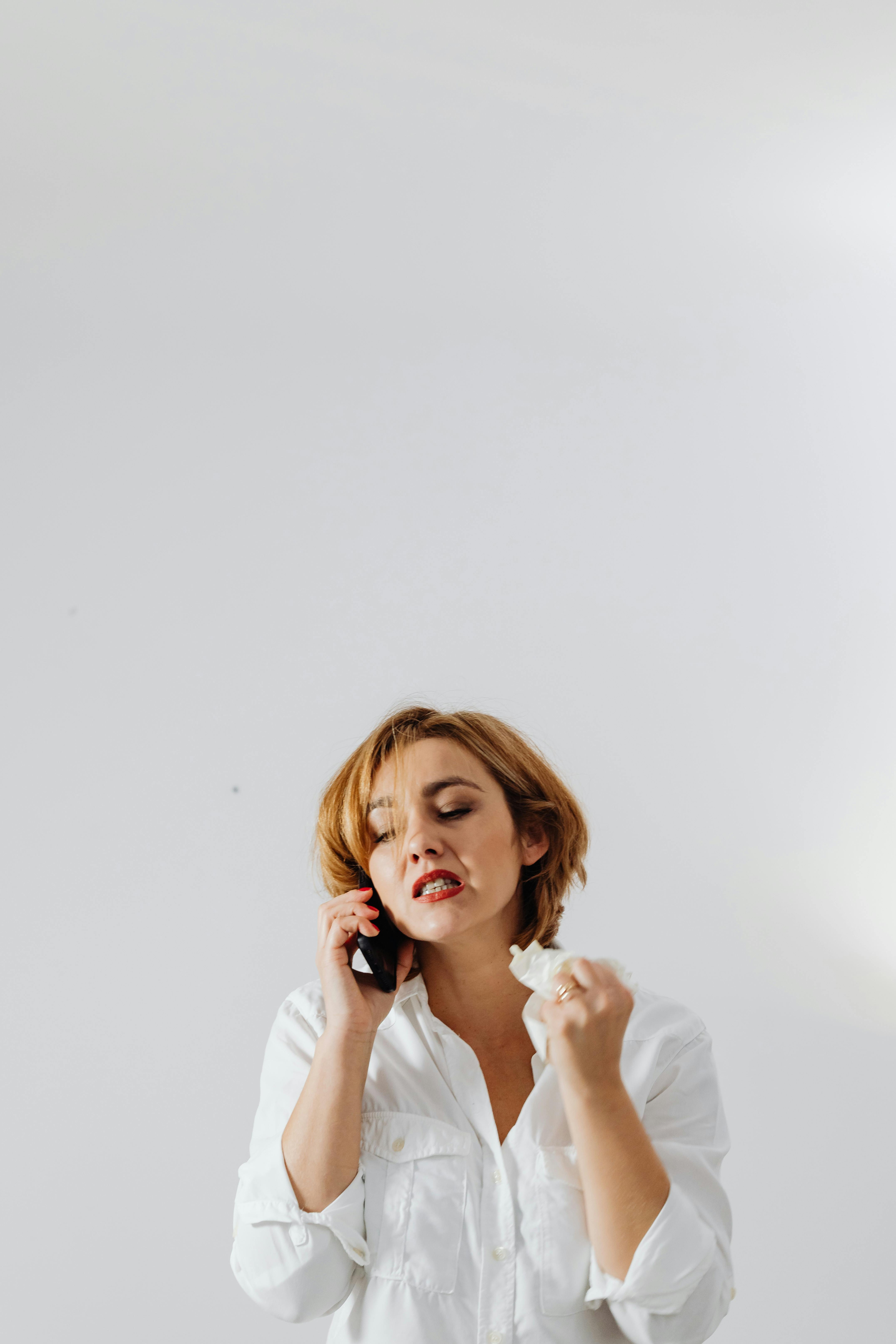 Eine aufgebrachte und wütende Frau hält ein Taschentuch in der Hand, während sie telefoniert | Quelle: Pexels