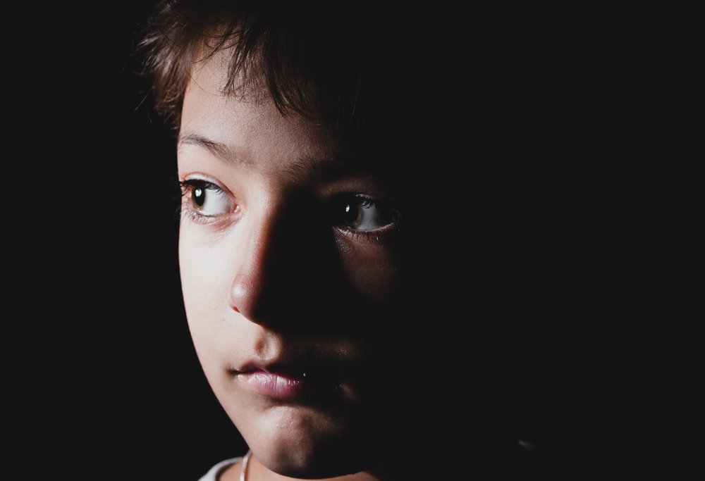 Das Foto eines Jungen, der Angst vor der Dunkelheit hat und auf eine Lichtquelle starrt. | Quelle: Shutterstock