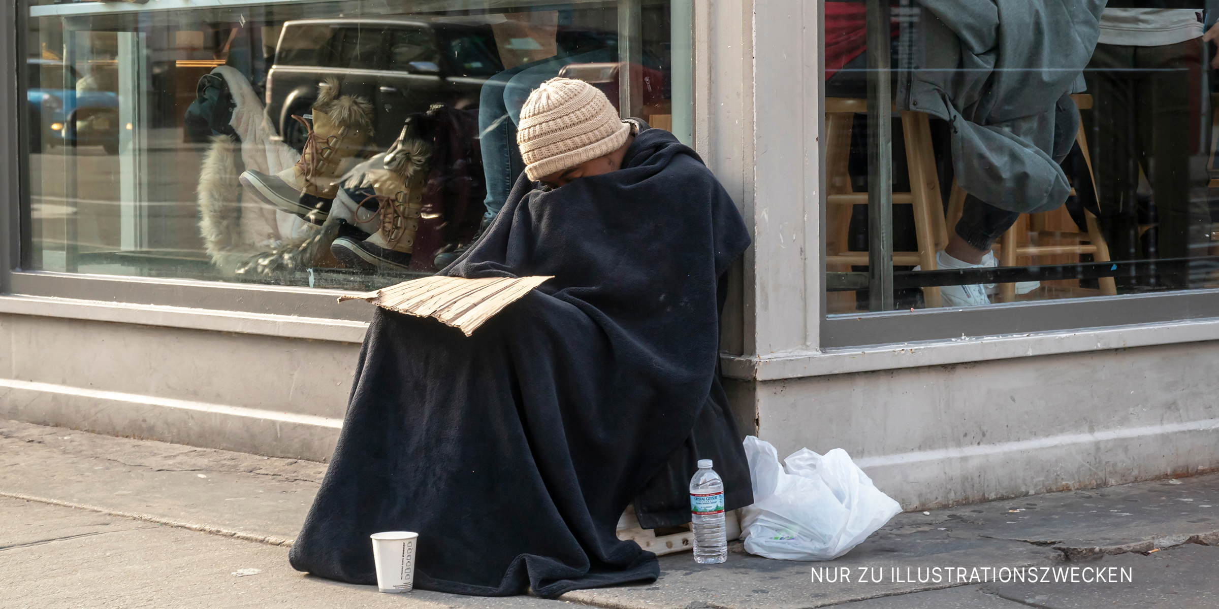 Obdachloser Mann sitzt vor einem Restaurant | Quelle: Shutterstock