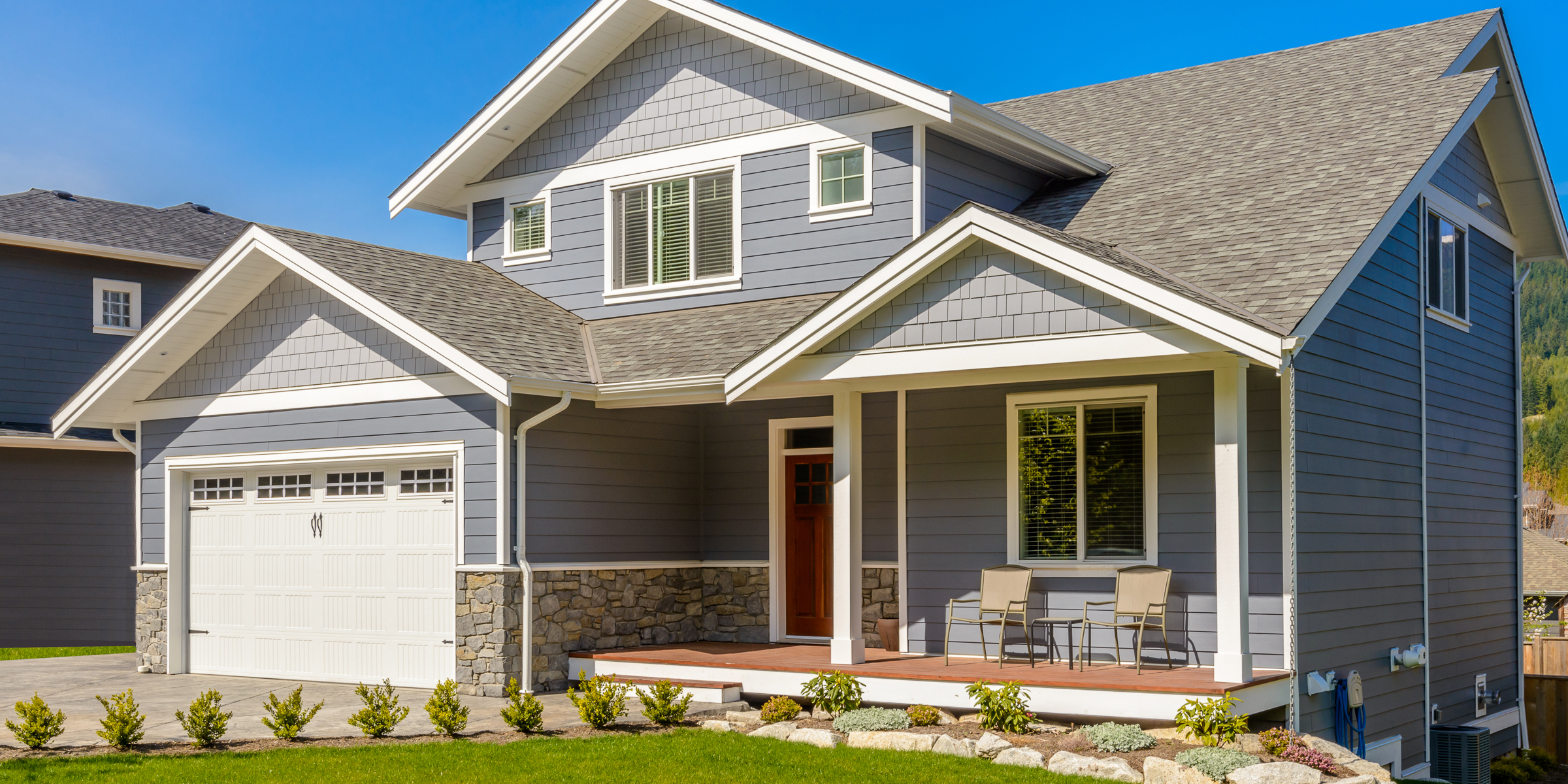 Ein modernes zweistöckiges Haus im grauen Craftsman-Stil mit überdachter Veranda und gepflegter Gartenanlage | Quelle: Shutterstock