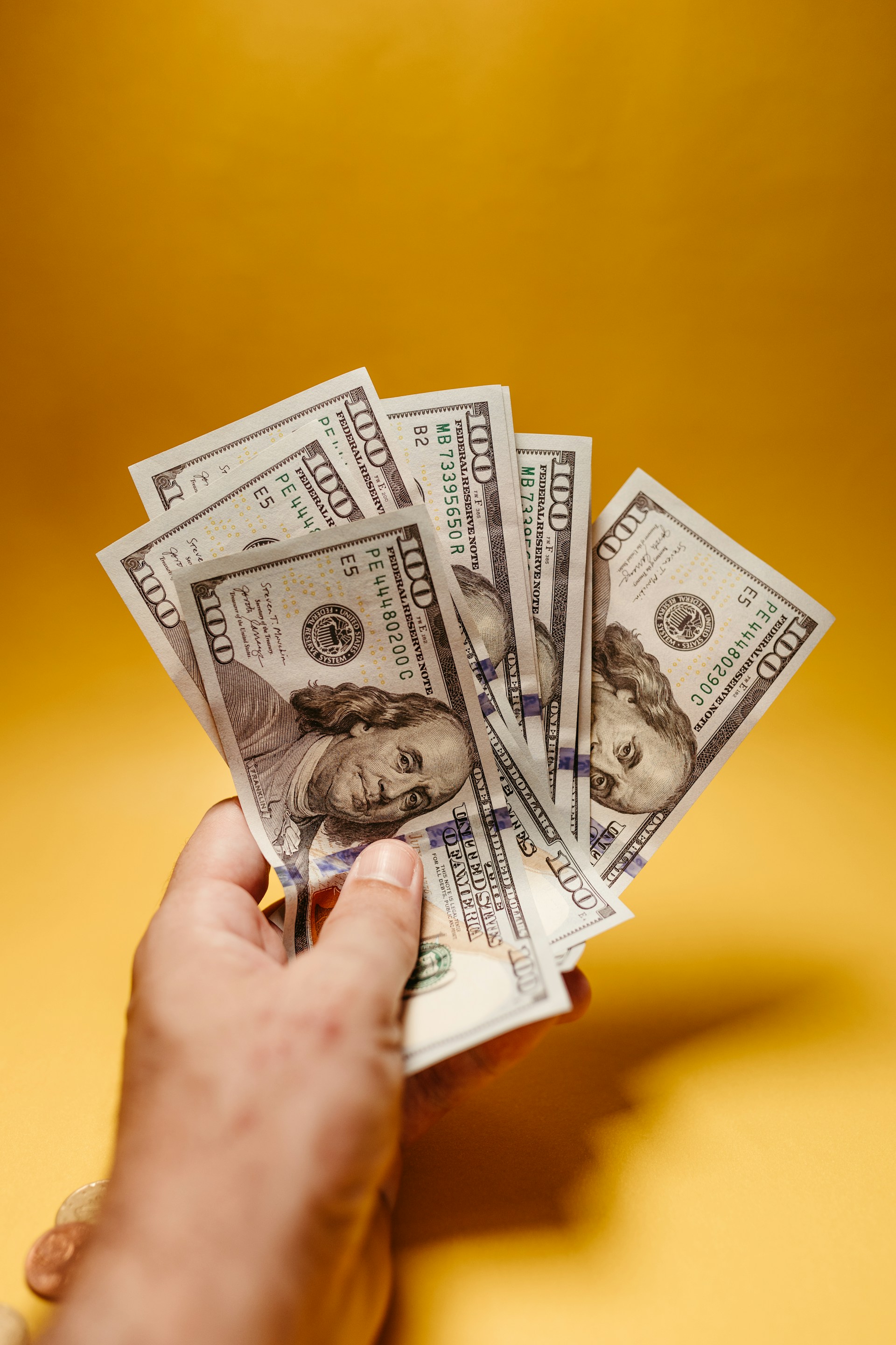 Ein Mann mit Hundertdollarscheinen in der Hand | Quelle: Unsplash