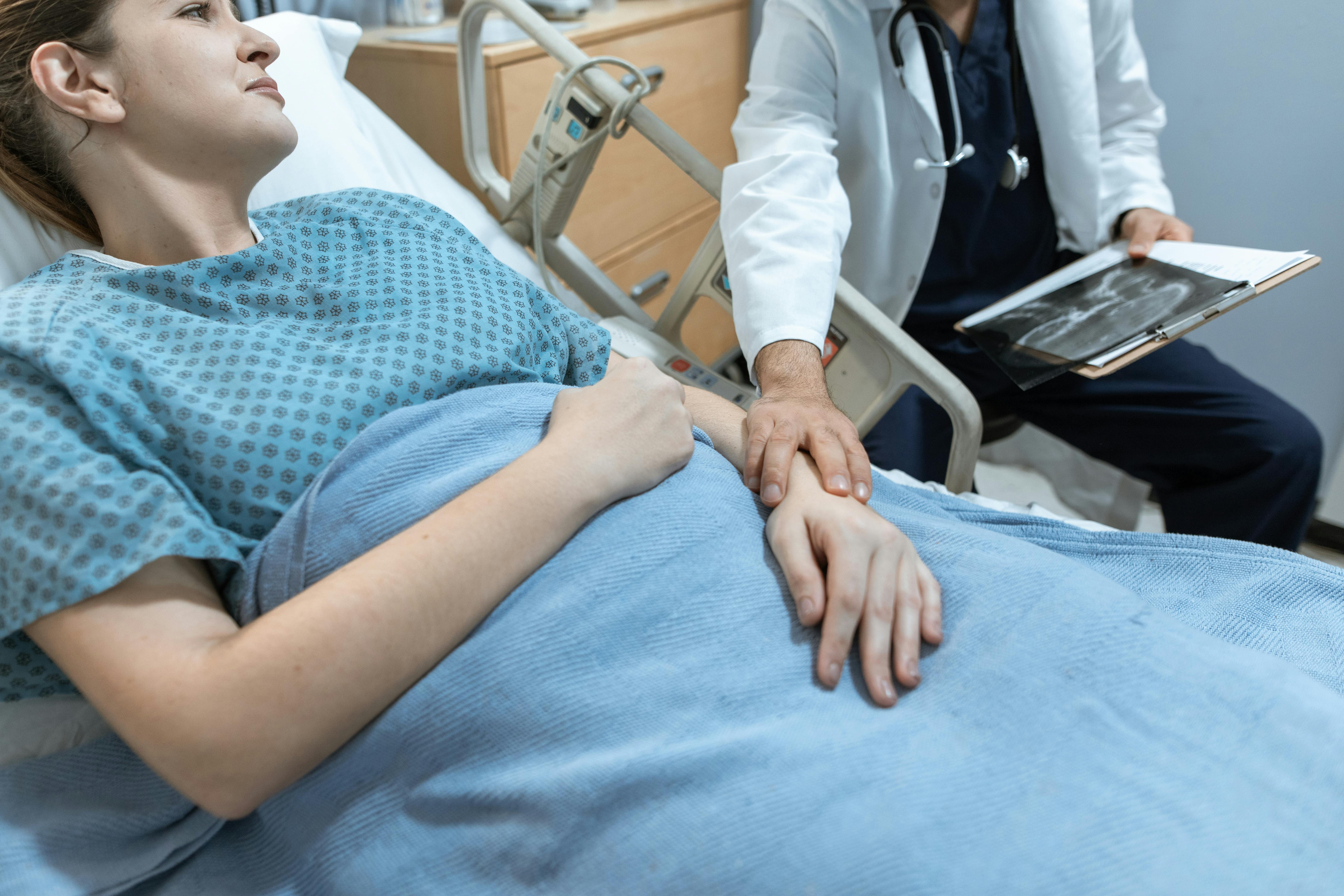 Eine Frau wird von einem Arzt getröstet, während sie in einem Krankenhausbett liegt | Quelle: Pexels