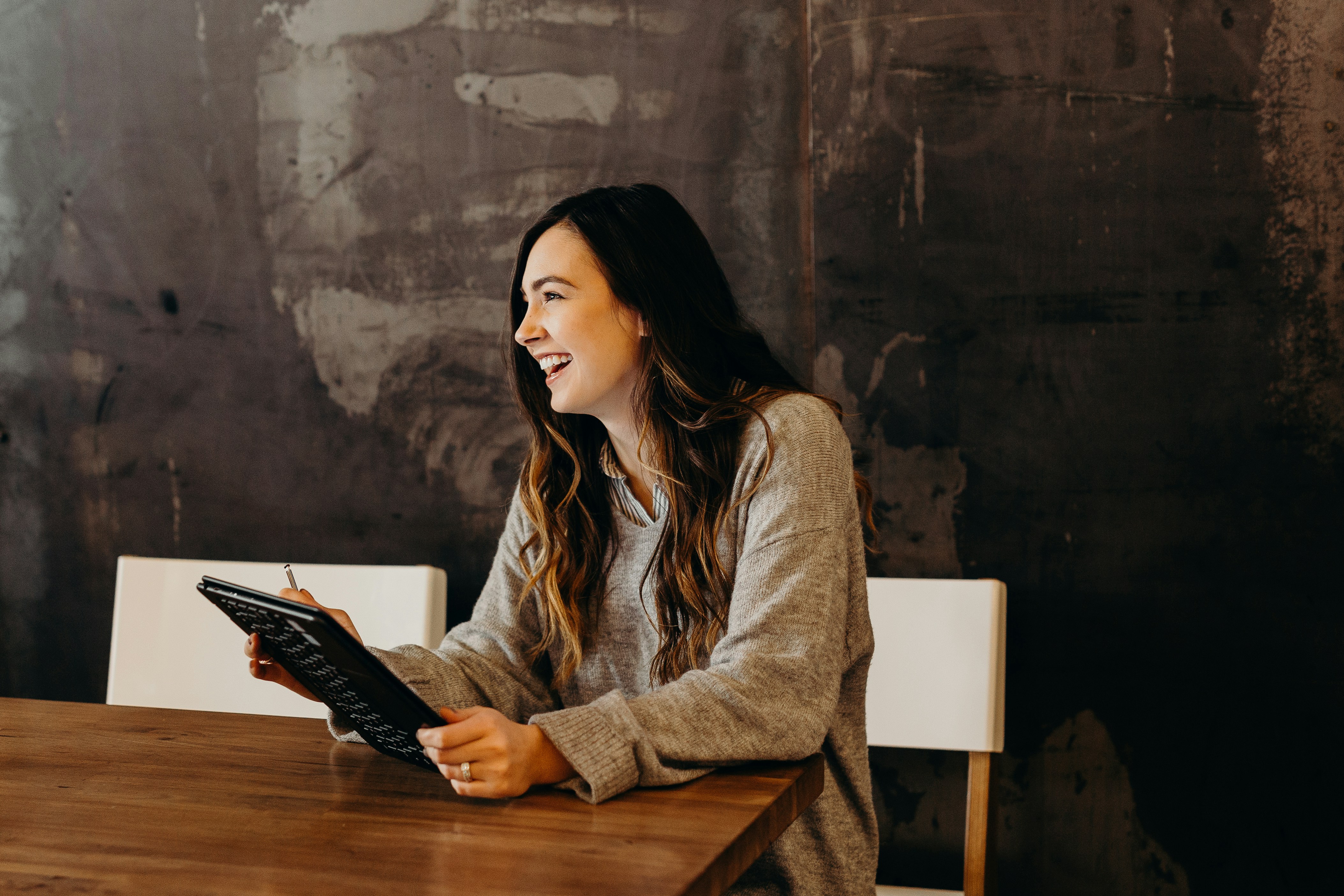 Eine lachende Frau am Arbeitsplatz | Quelle: Unsplash