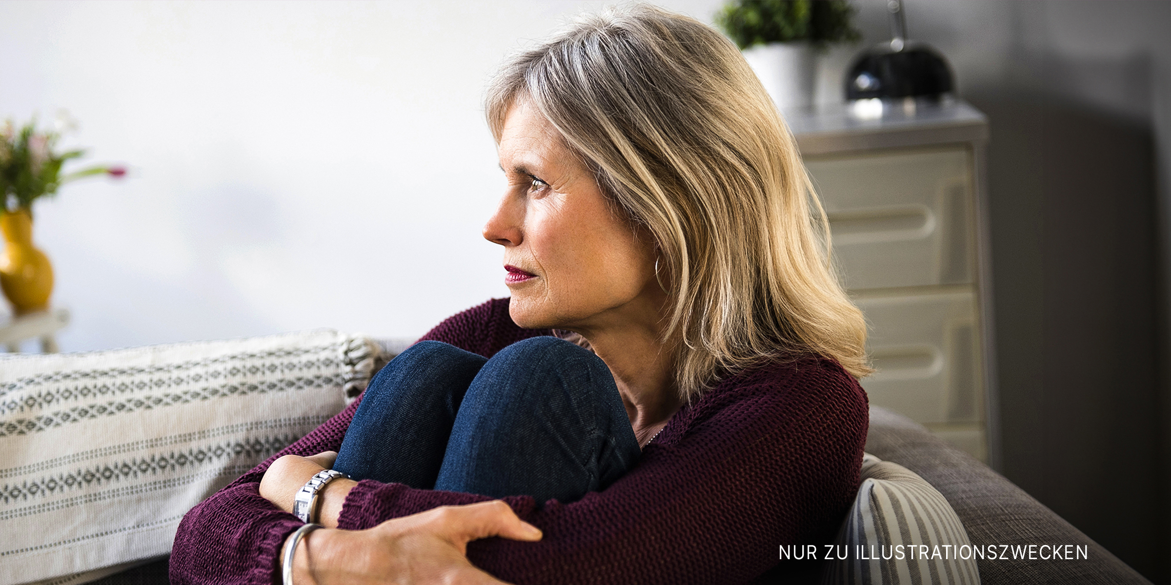 Eine Frau, die auf der Couch sitzt und traurig aussieht | Quelle: Shutterstock