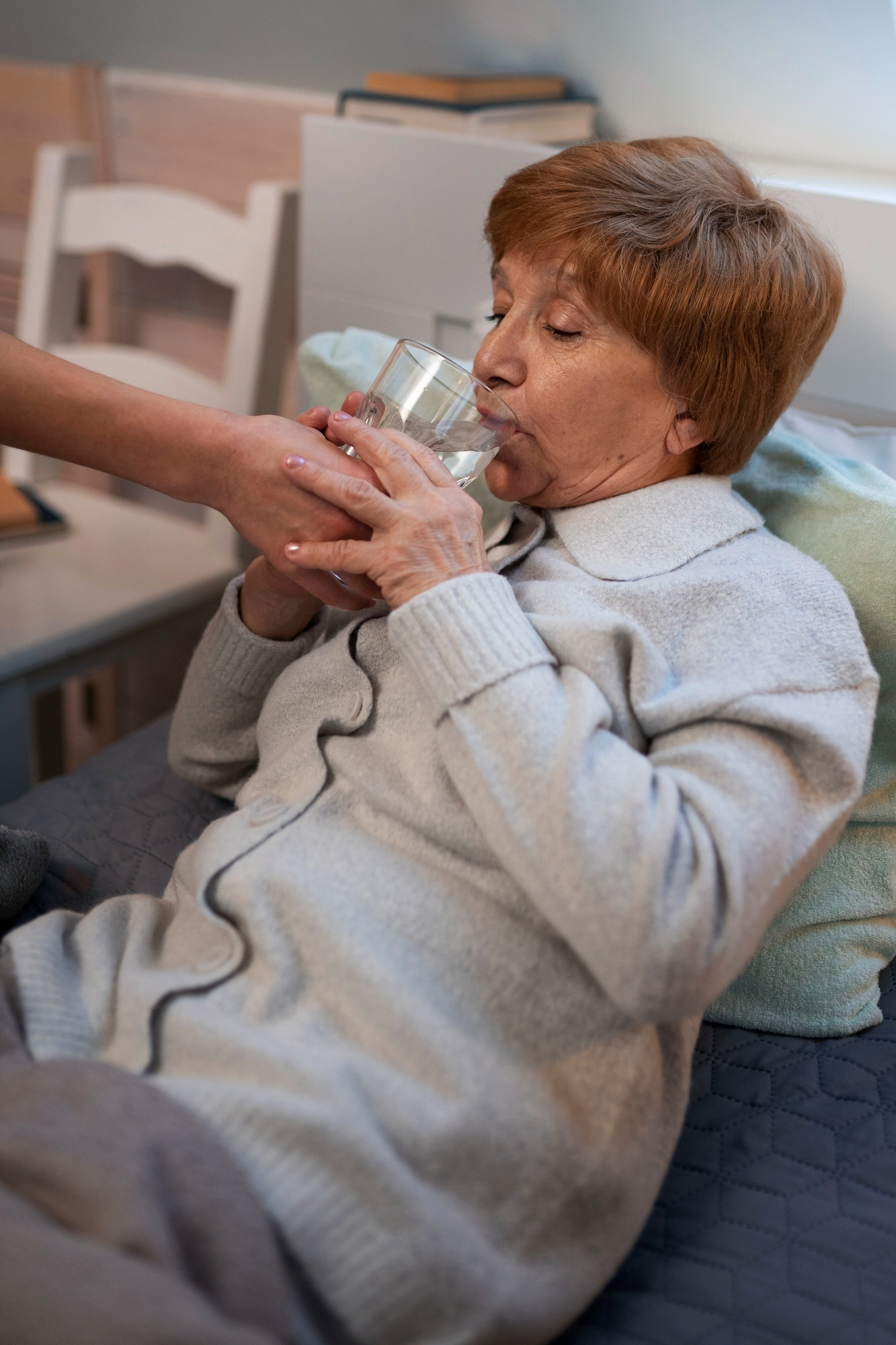 Eine Frau hilft einer kranken Frau mittleren Alters, Wasser zu trinken | Quelle: Freepik