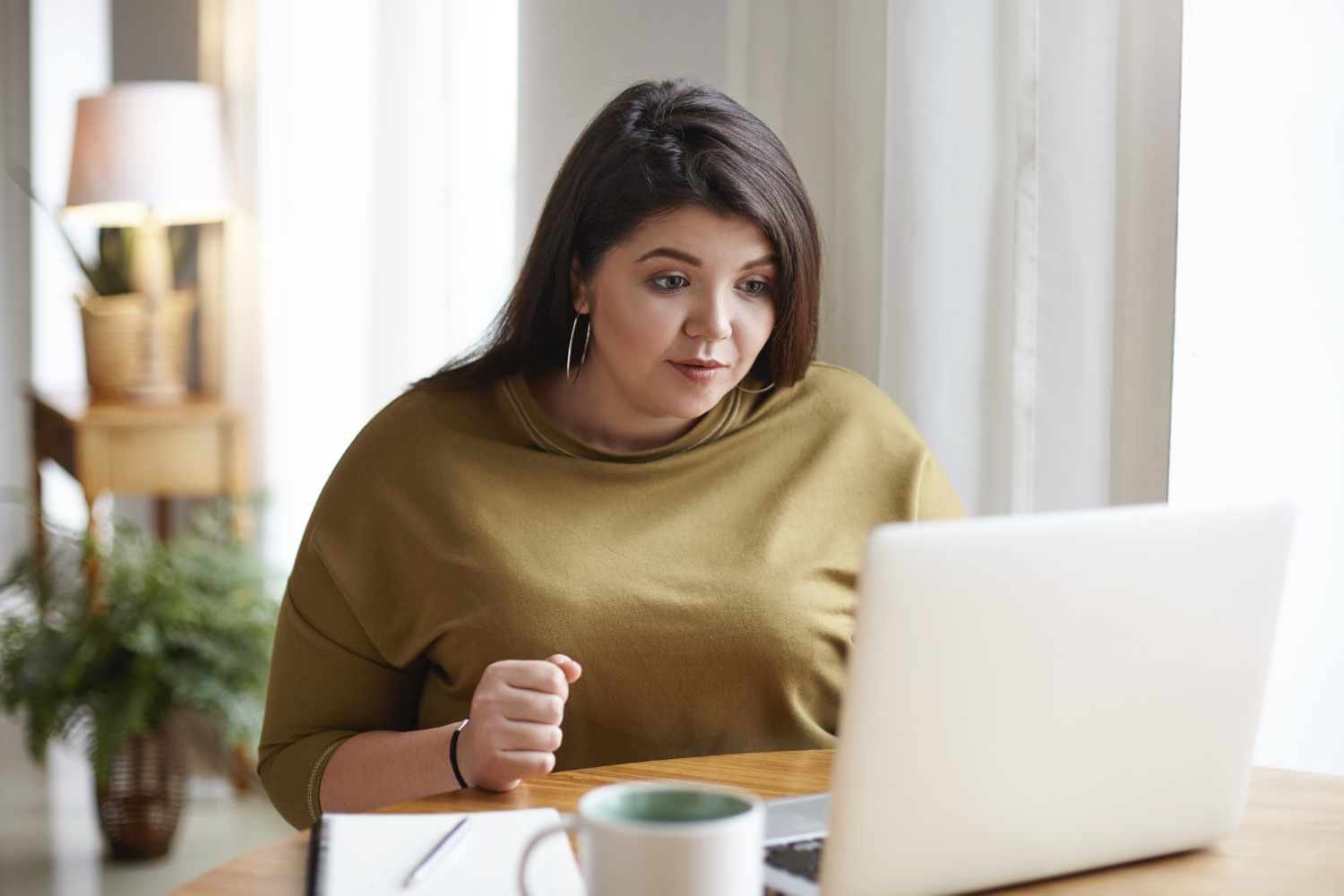 Eine erfreute Frau schaut auf ihren Laptop | Quelle: Freepik