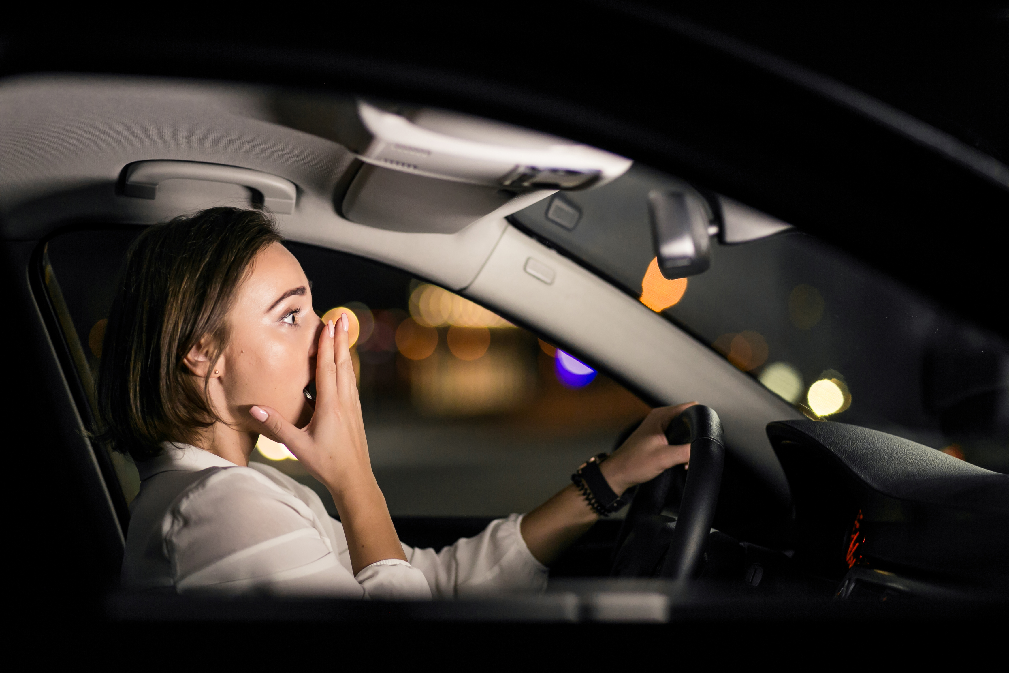 Foto noturna de uma mulher chocada dirigindo um carro | Fonte: Freepik