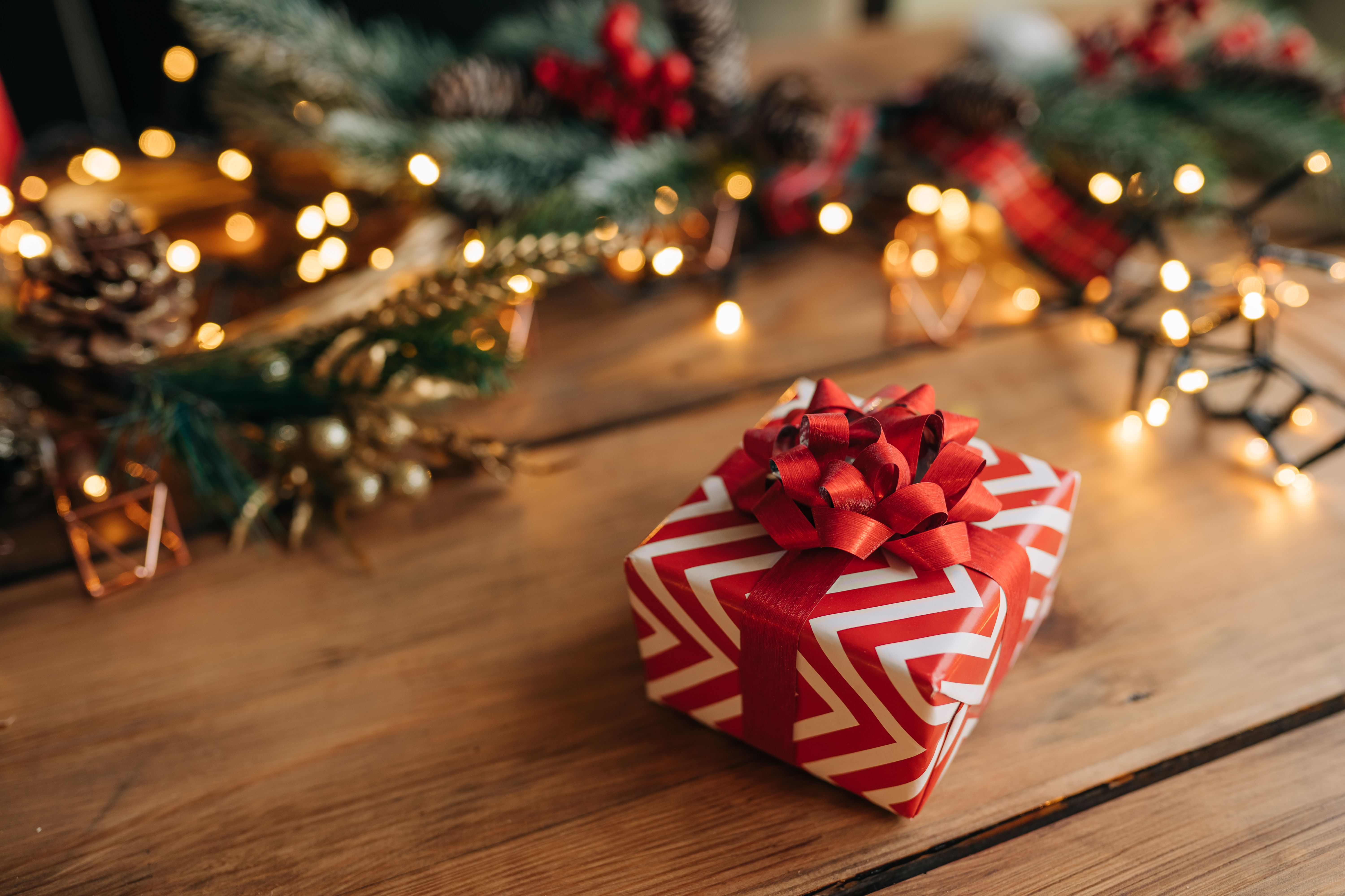 Ein rot-weißes Weihnachtsgeschenk auf einem Holztisch. | Quelle: Getty Images