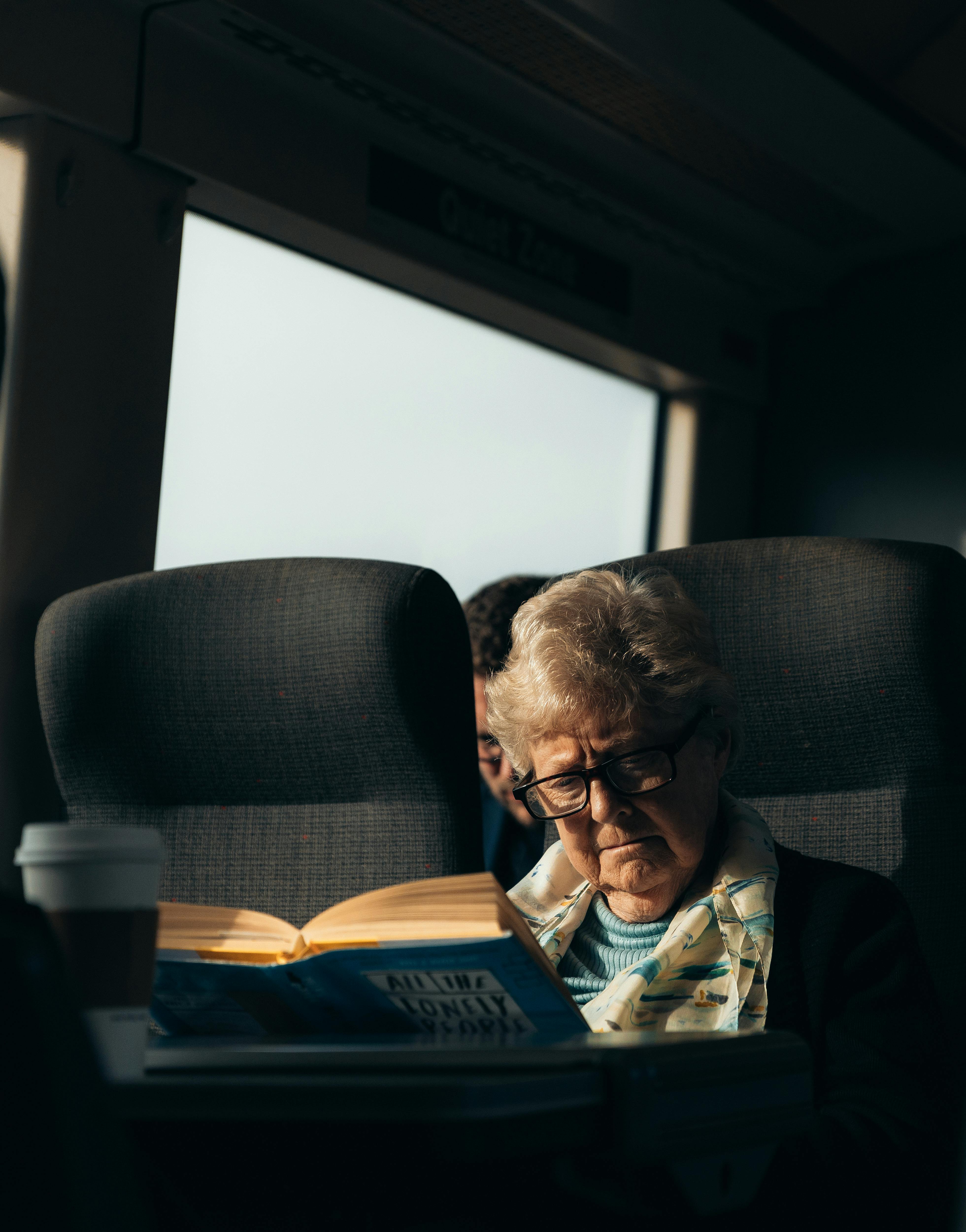 Eine ältere Frau, die ein Buch liest, während sie mit dem Zug reist | Quelle: Pexels
