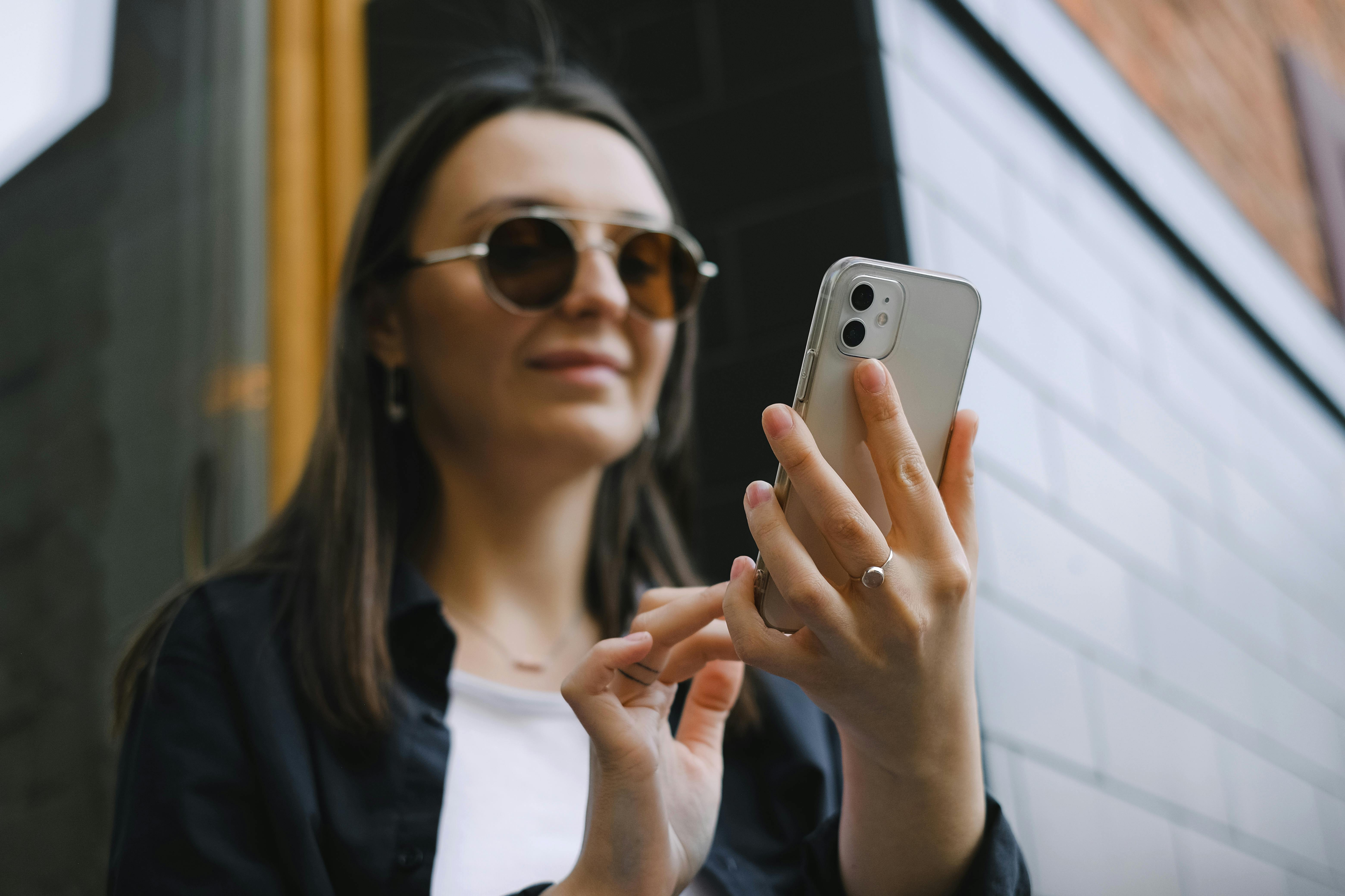 Eine lächelnde Frau, die auf ihrem Telefon tippt | Quelle: Pexels