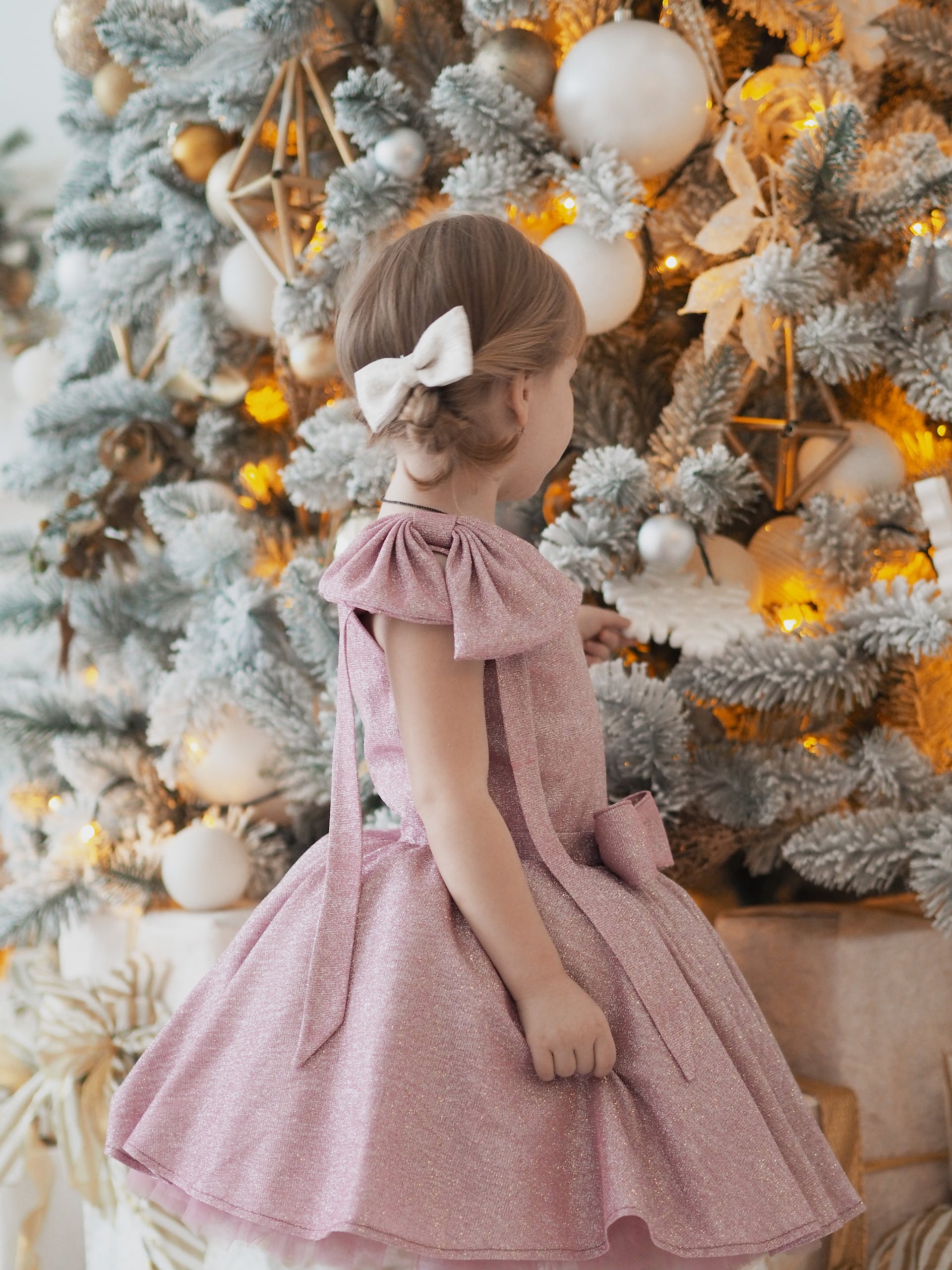 Ein kleines Mädchen schaut sich einen Weihnachtsbaum an | Quelle: Pexels