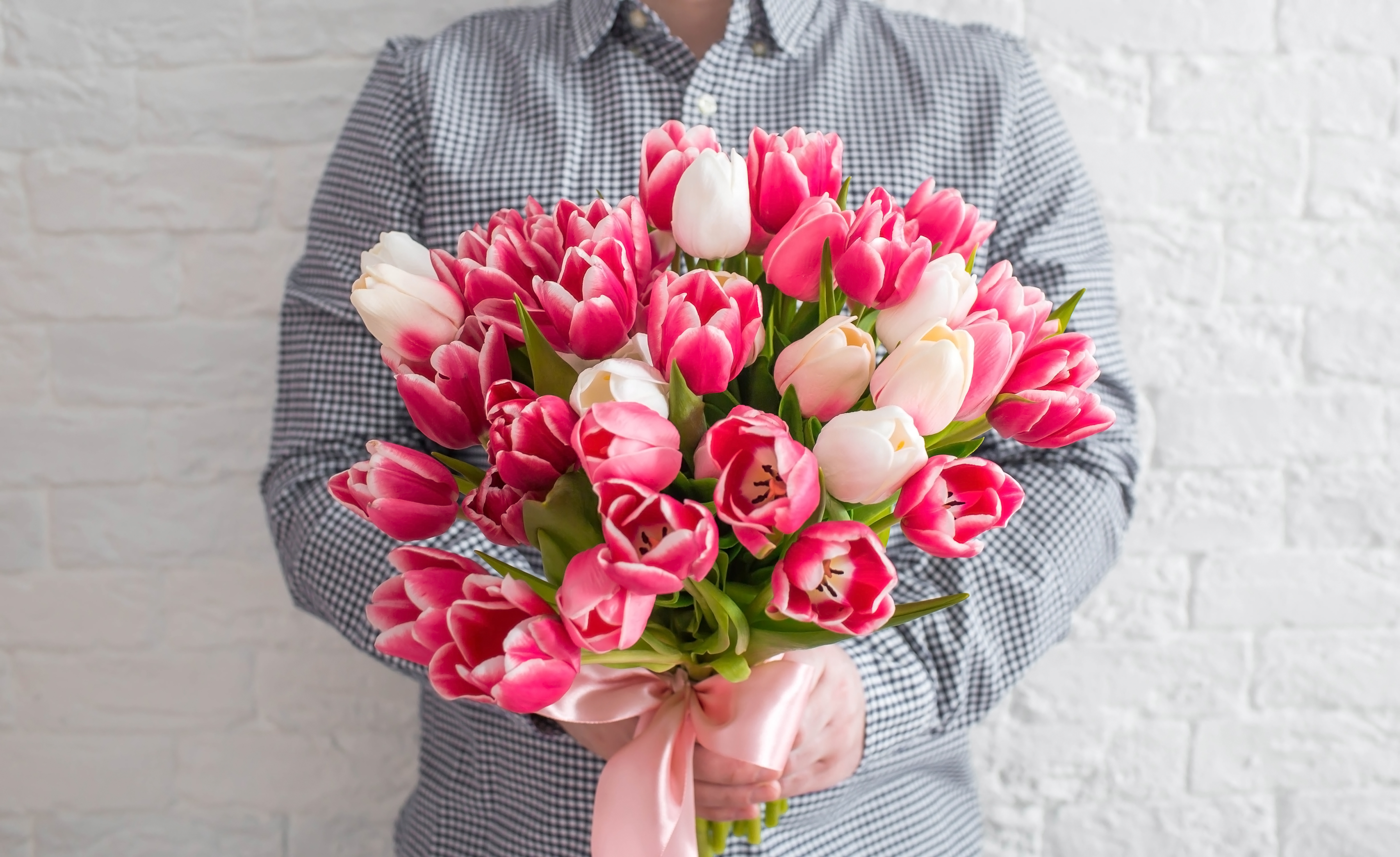 Ein junger Mann hält Blumen | Quelle: Shutterstock