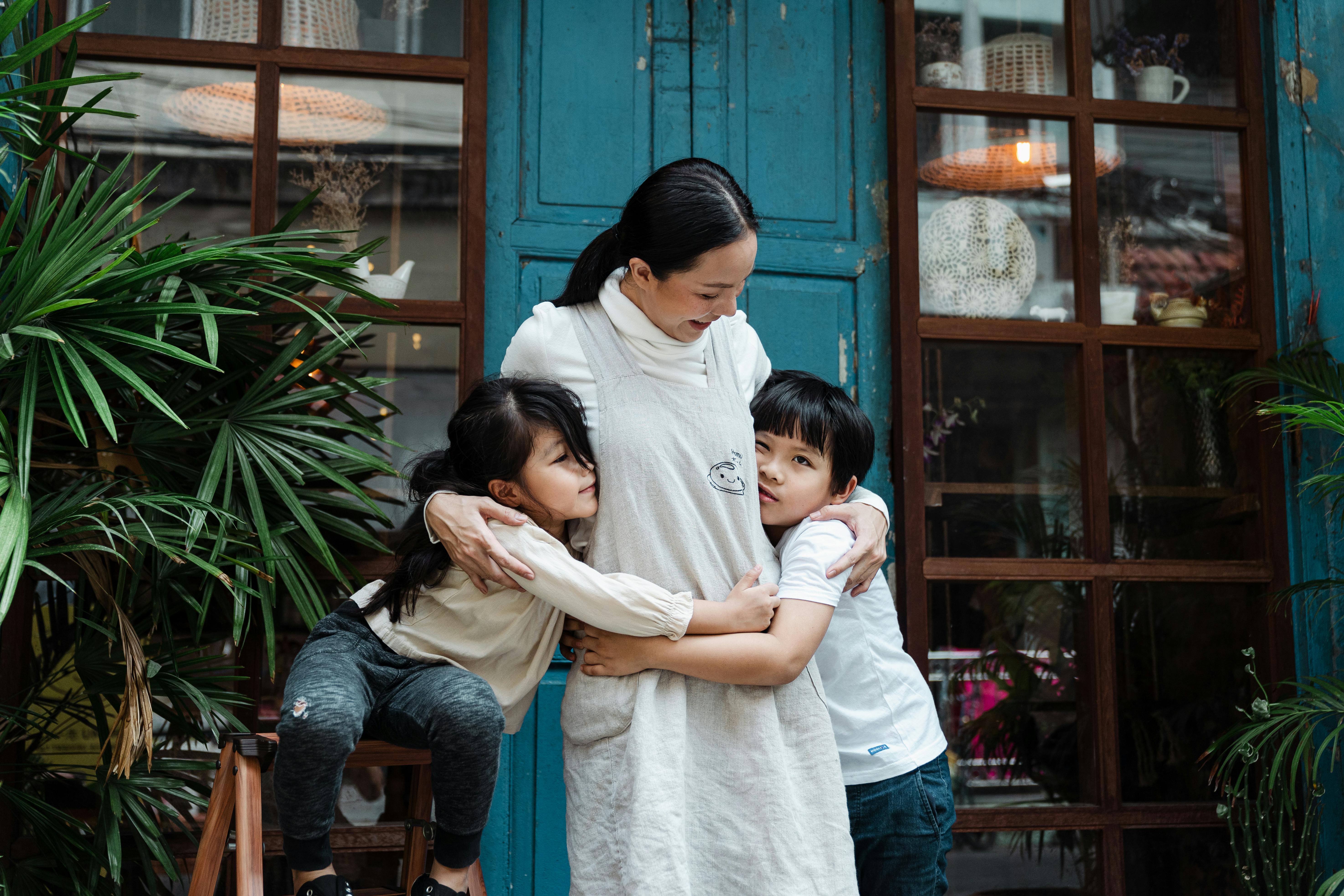 Eine Frau, die zwei kleine Kinder umarmt | Quelle: Pexels