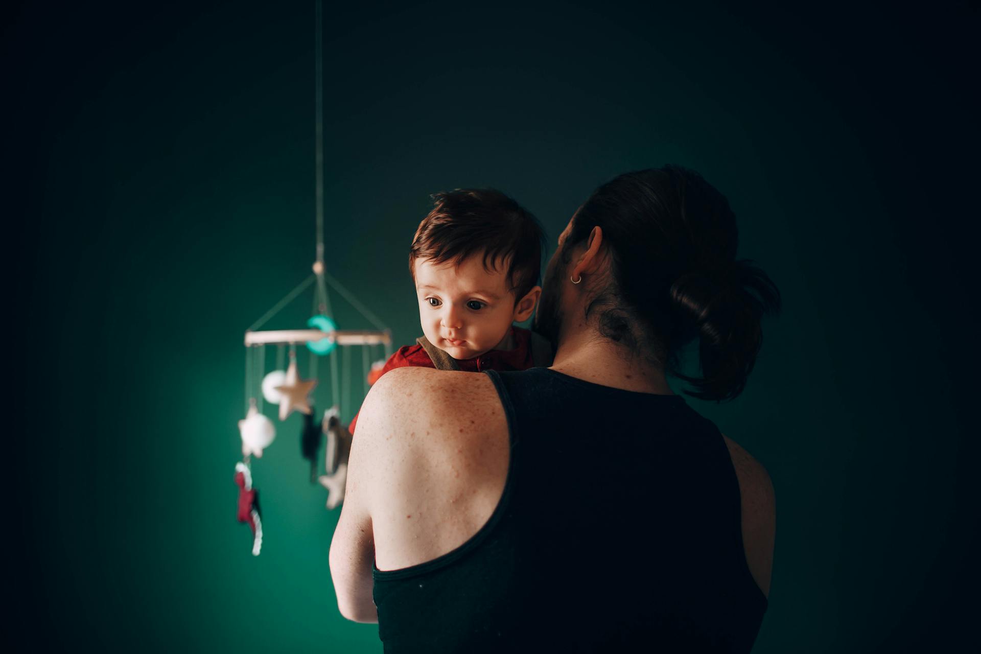 Ein Mann schaukelt ein Baby in einem Kinderzimmer | Quelle: Pexels