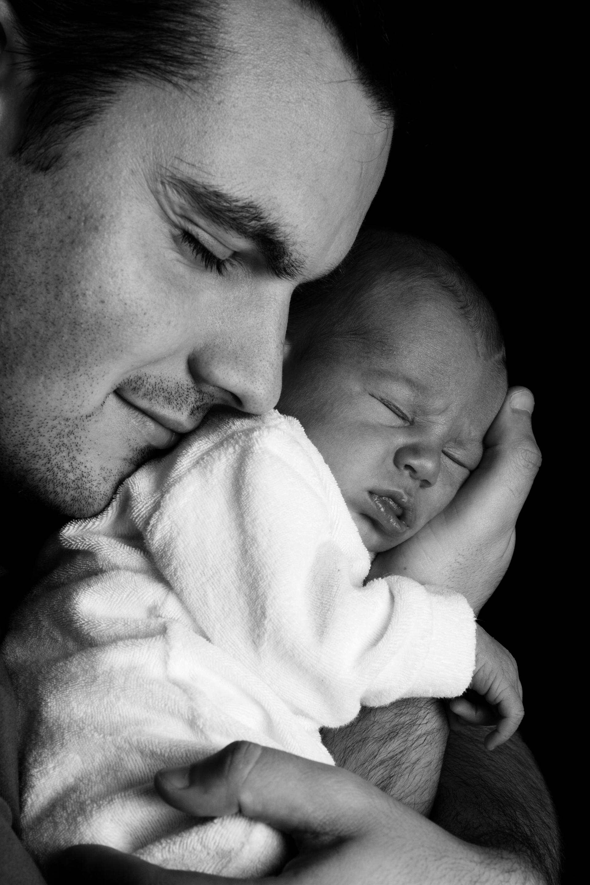 Graustufenfoto eines Mannes, der ein neugeborenes Baby trägt | Quelle: Pexels