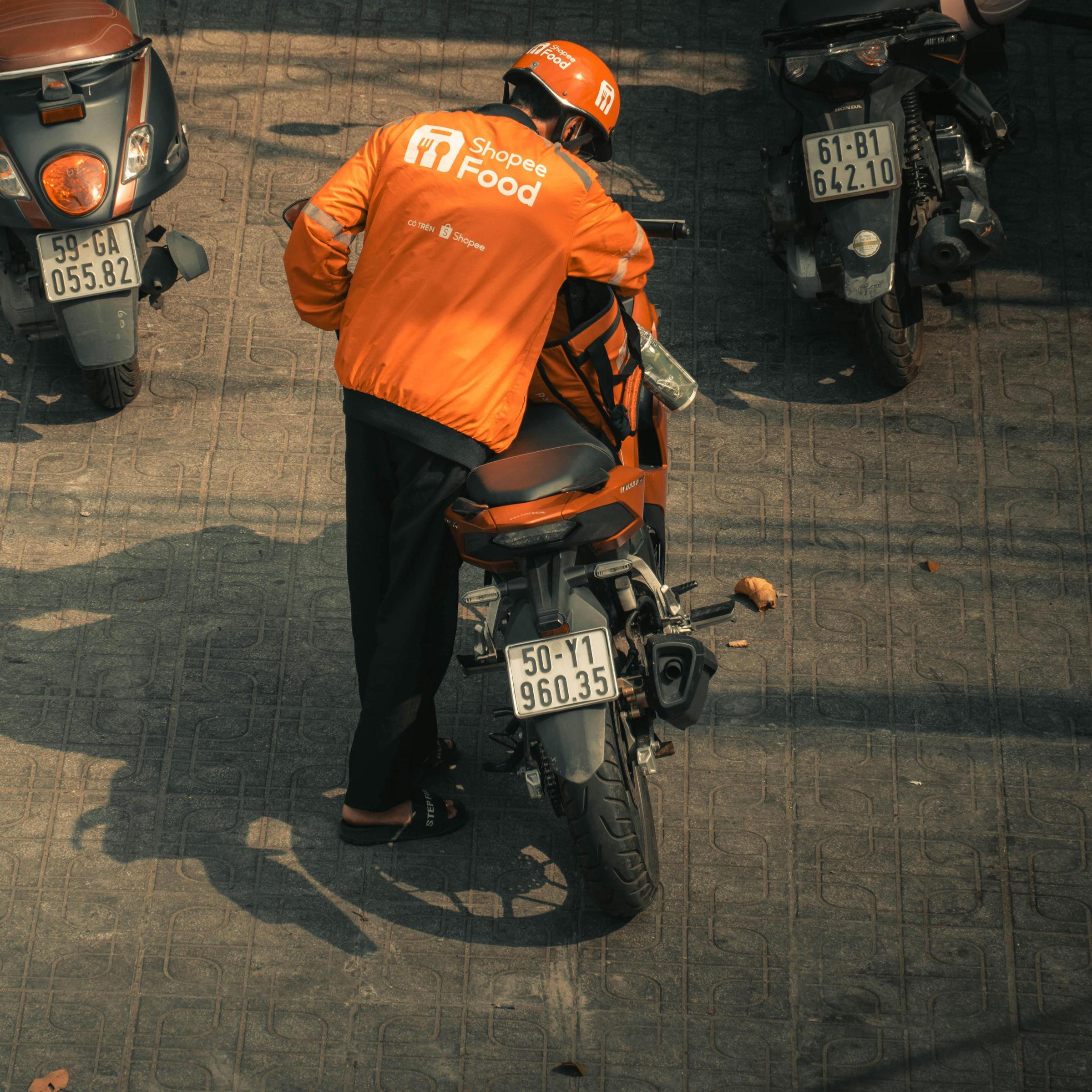 Ein Lebensmittellieferant, der auf sein Motorrad aufsattelt | Quelle: Pexels