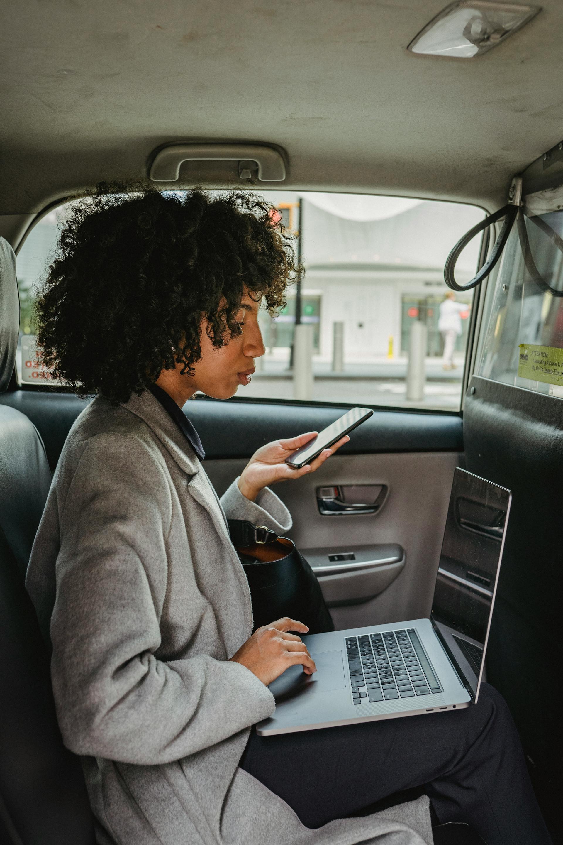 Eine ernste Frau, die ein Telefon hält und einen Laptop benutzt | Quelle: Pexels