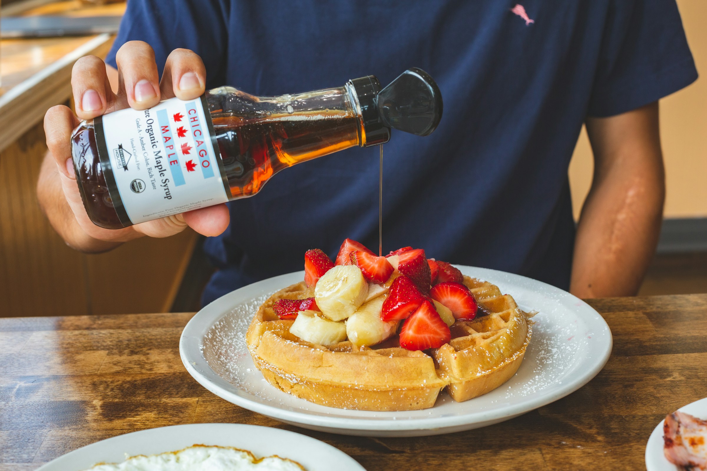 Eine Person gießt Sirup auf Waffeln | Quelle: Unsplash