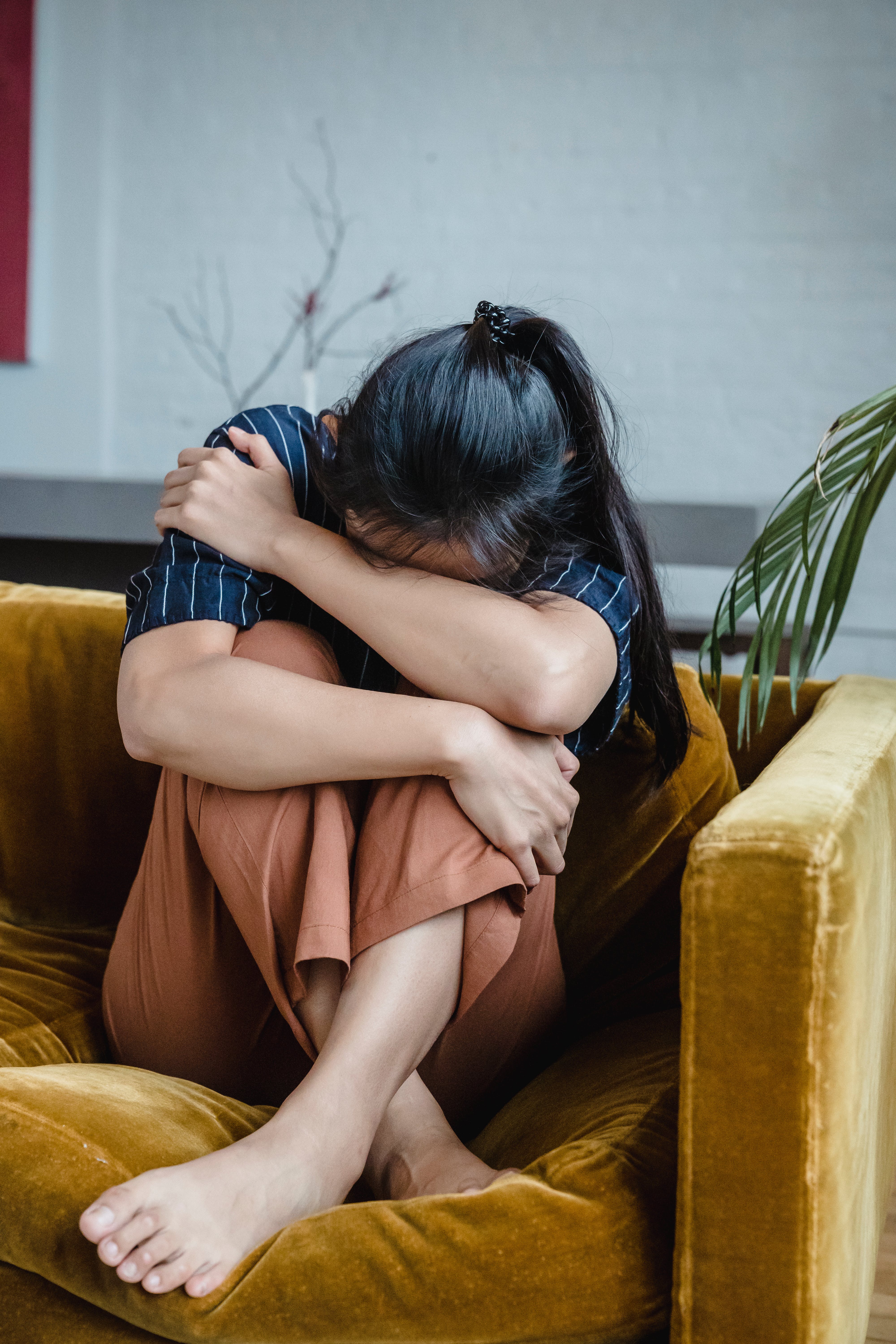 Eine Frau, die sich weinend auf der Couch zusammengerollt hat | Quelle: Pexels